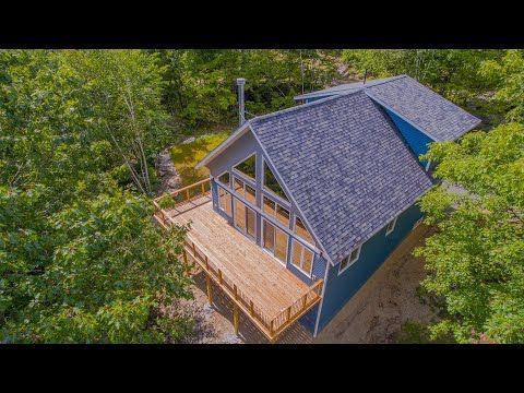 An aerial view of a blue house with a large deck surrounded by trees.