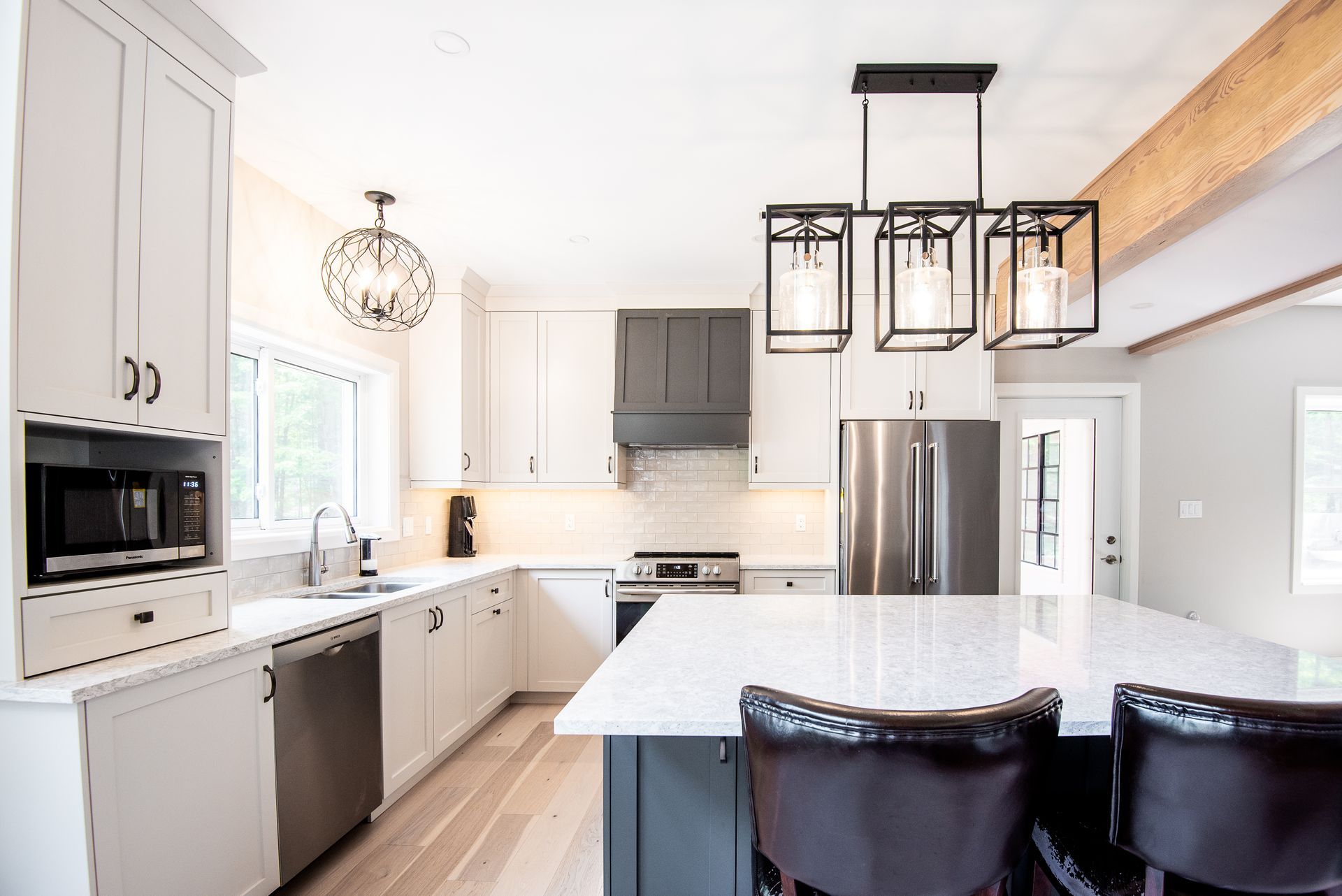 A kitchen with white cabinets , stainless steel appliances , and a large island.
