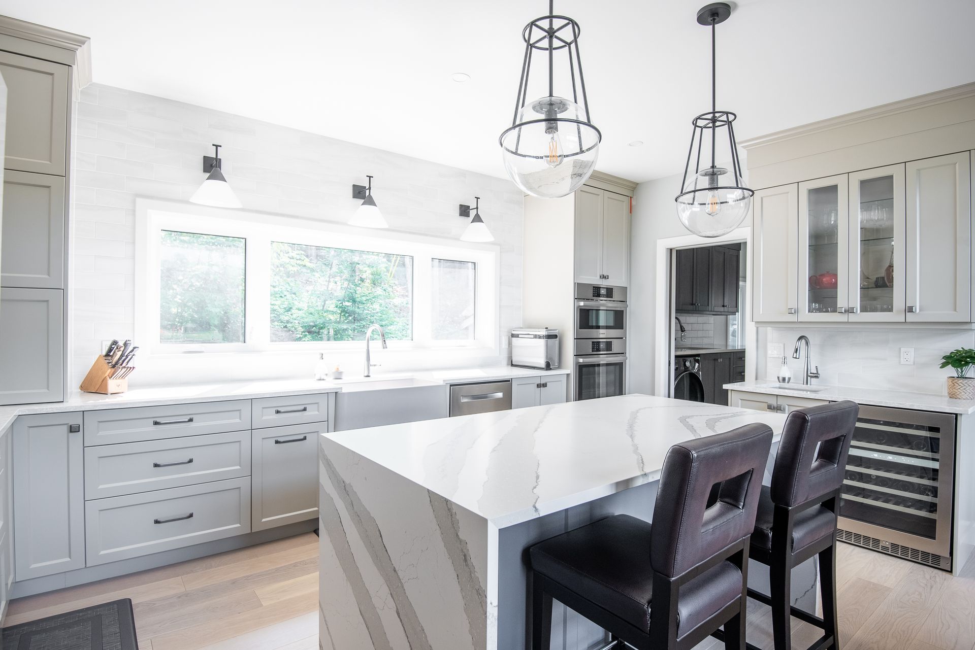 A kitchen with white cabinets , a large island , and two bar stools.