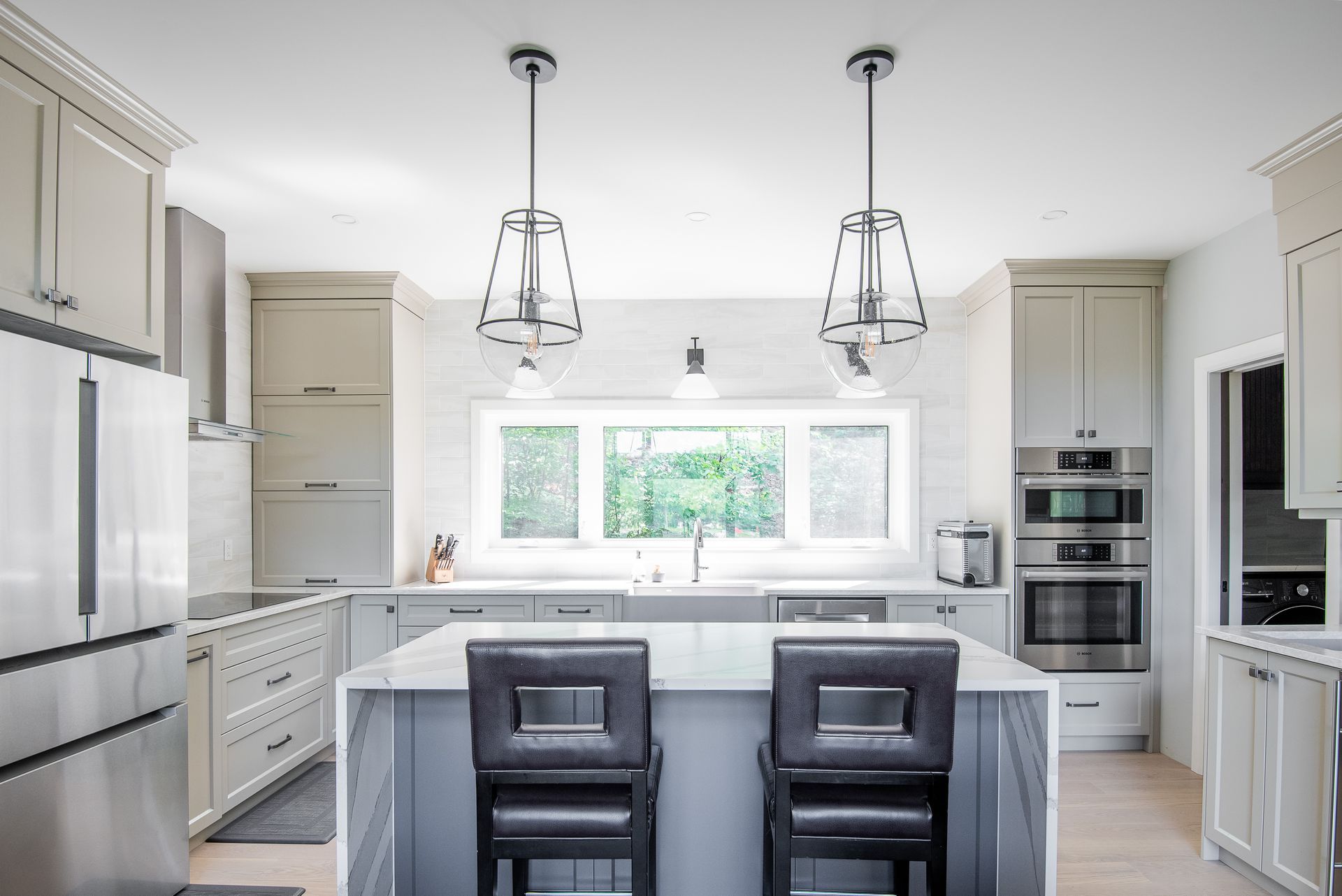 A kitchen with stainless steel appliances and a large island with two chairs.