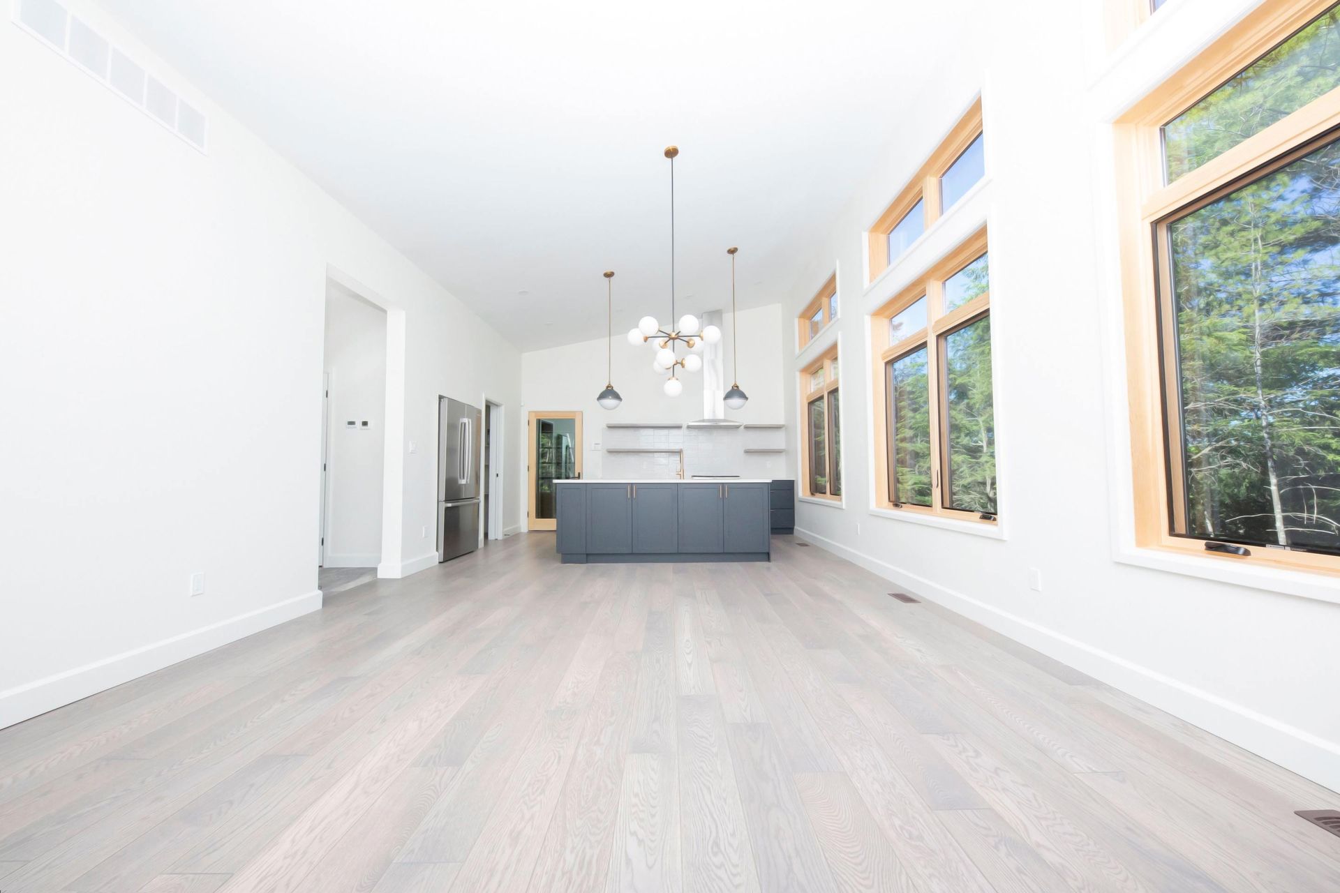 A large empty room with a kitchen and a lot of windows.