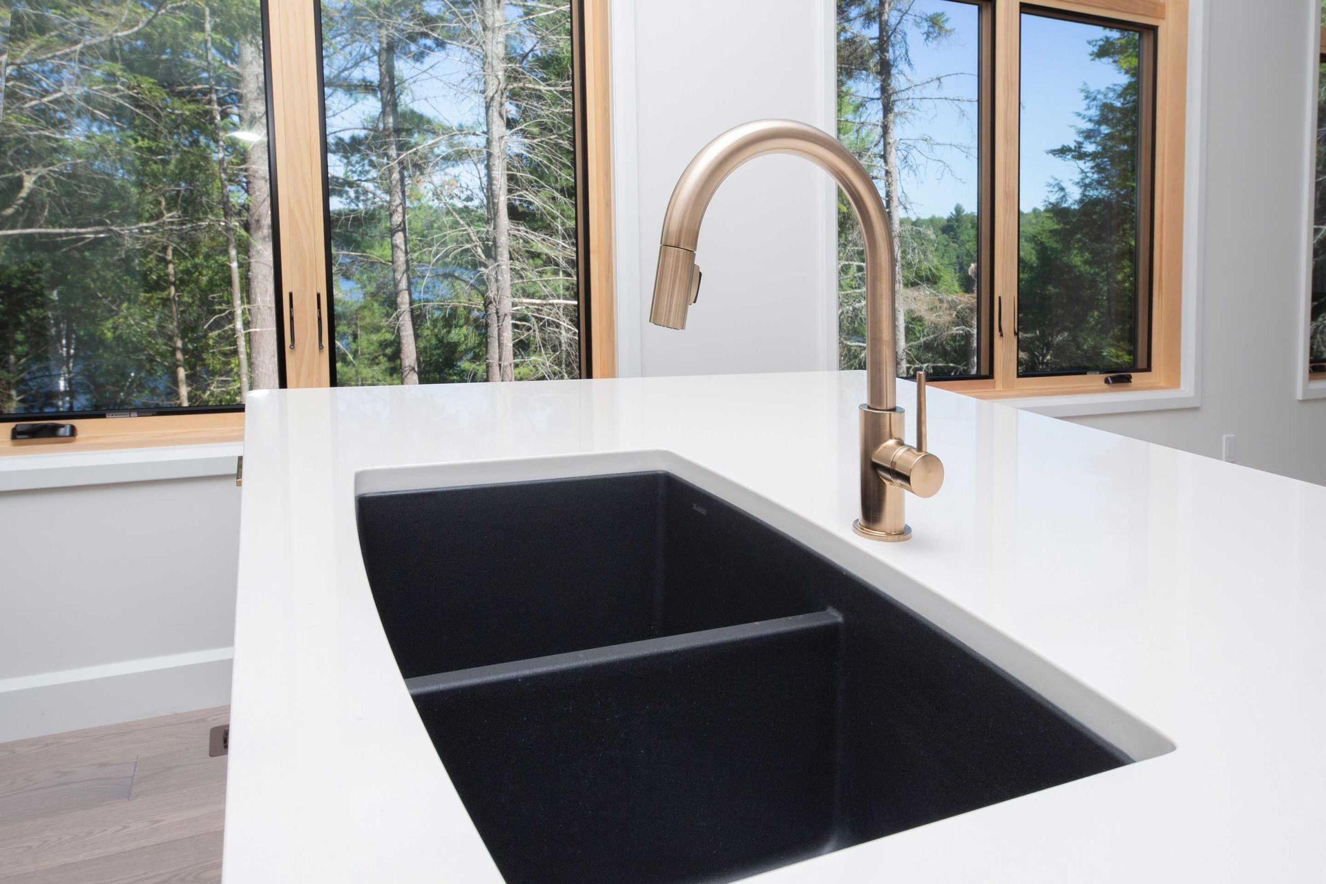 A kitchen sink with a faucet and a window in the background.