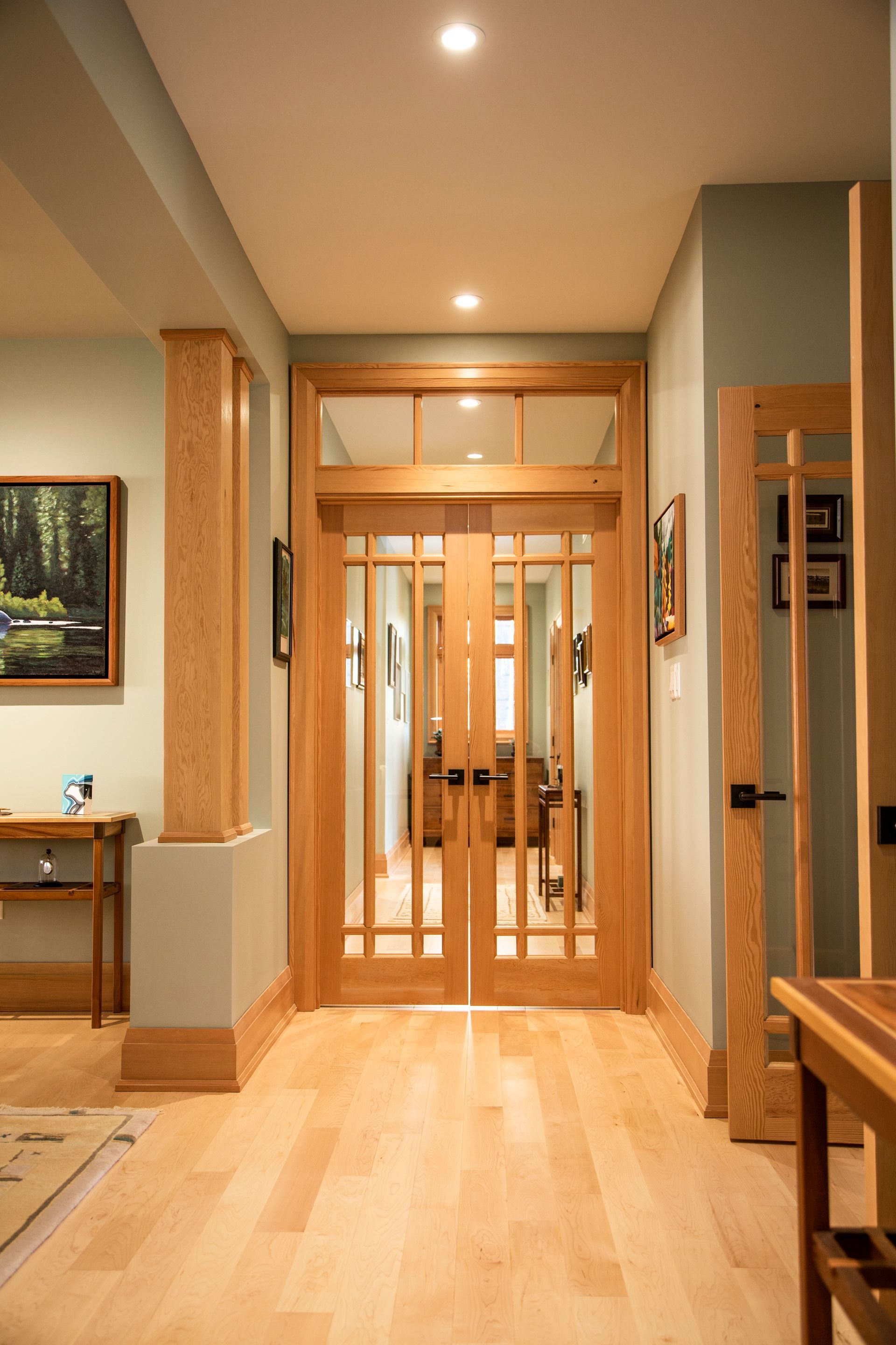 A hallway in a house with wooden doors and a painting on the wall.