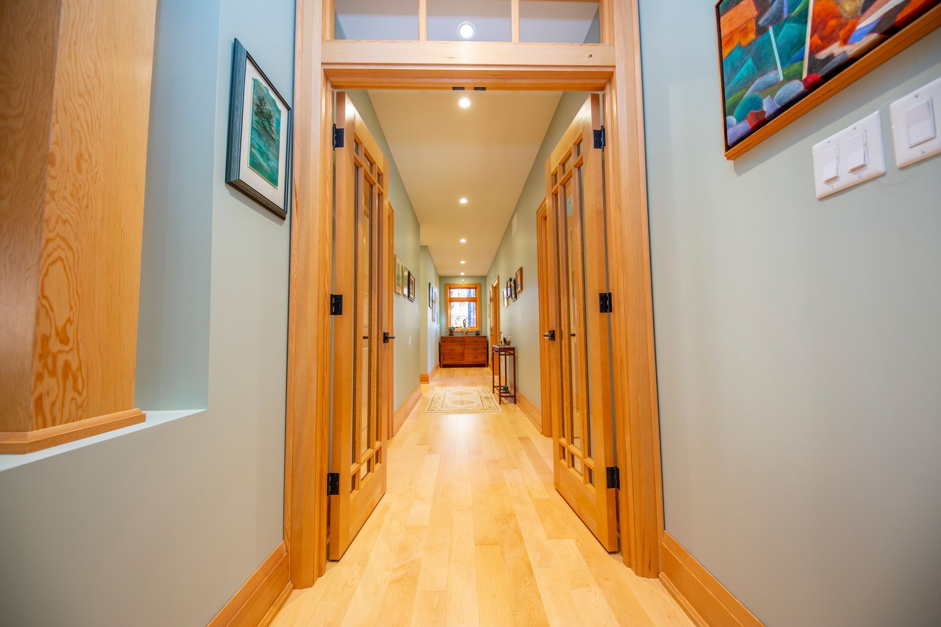 A long hallway with wooden floors and doors in a house.