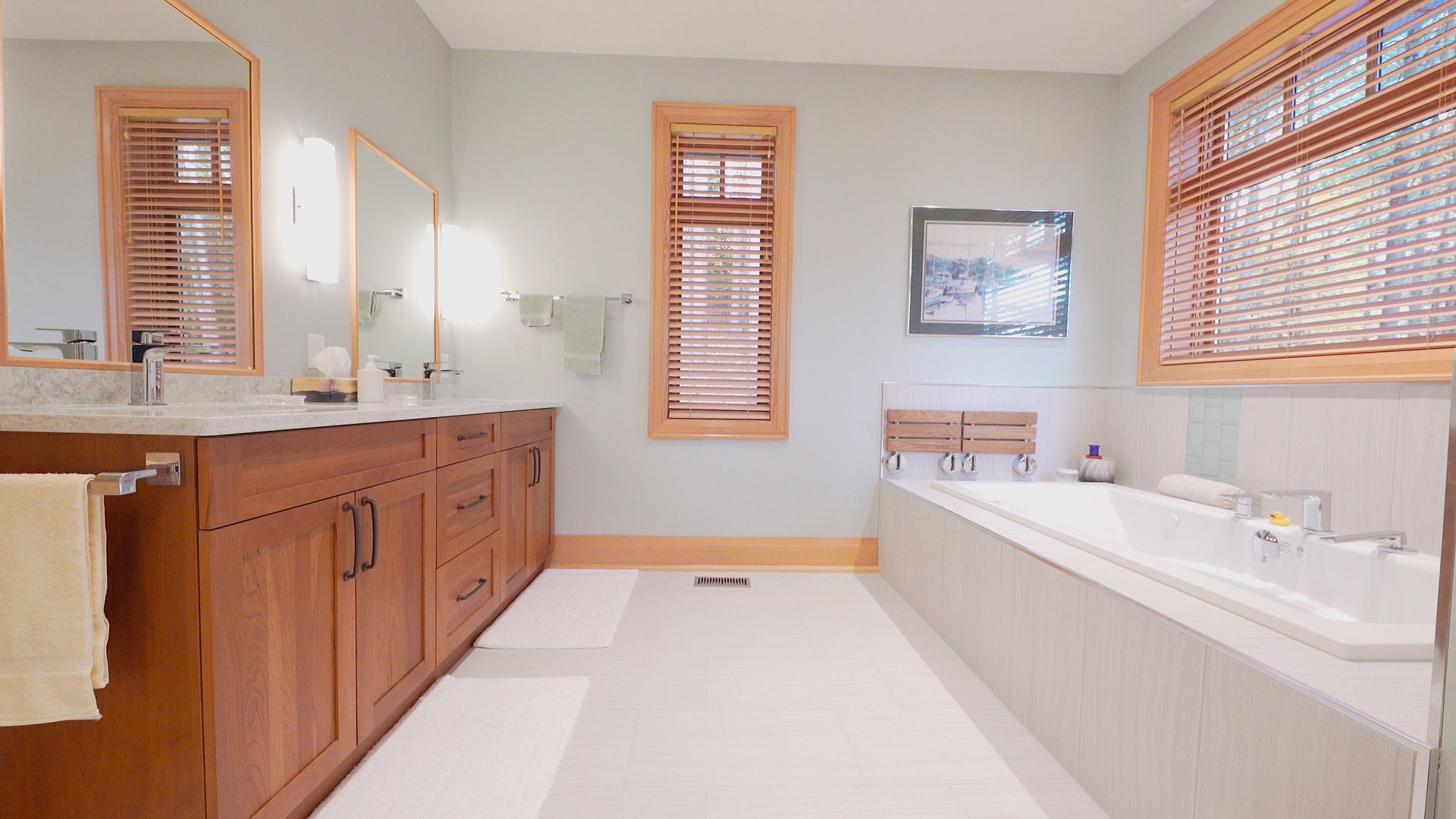 A bathroom with two sinks , a tub , a mirror and two windows.