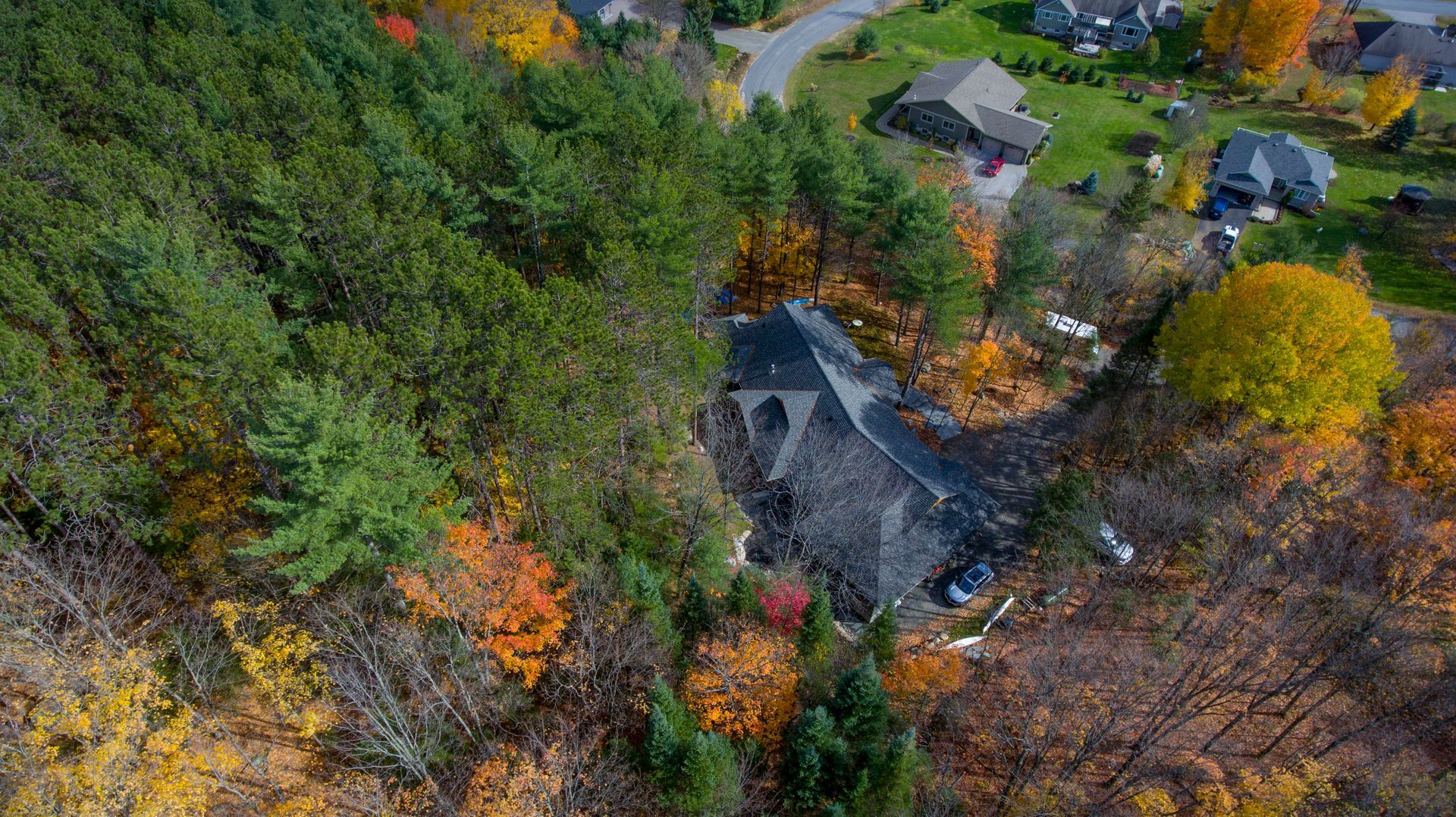 An aerial view of a house in the middle of a forest surrounded by trees.