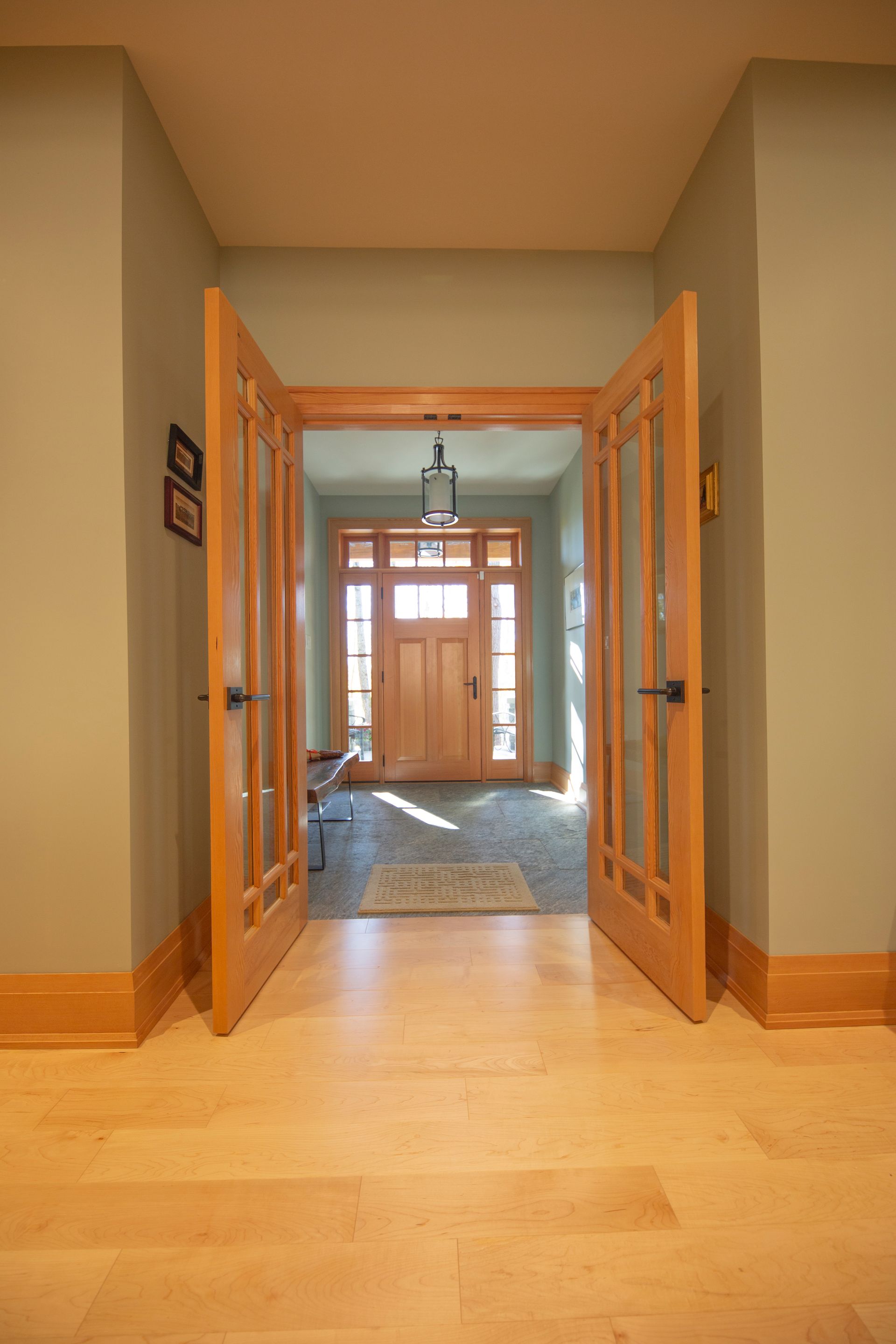 A hallway with wooden floors and double doors leading to a doorway.
