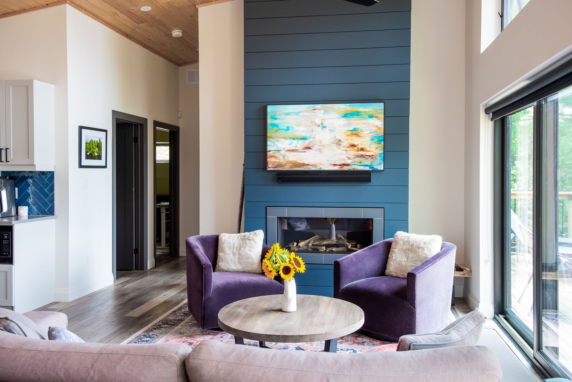 A living room with a fireplace , couch , chairs , table and television.