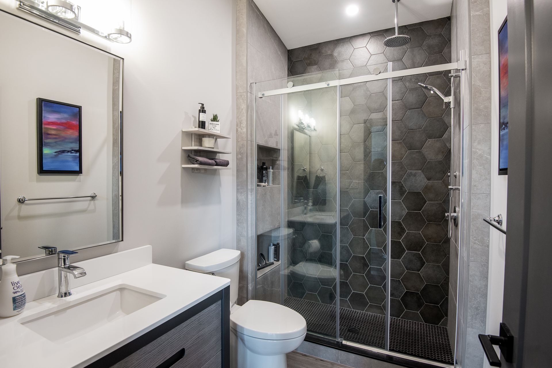 A bathroom with a toilet , sink , shower and mirror.