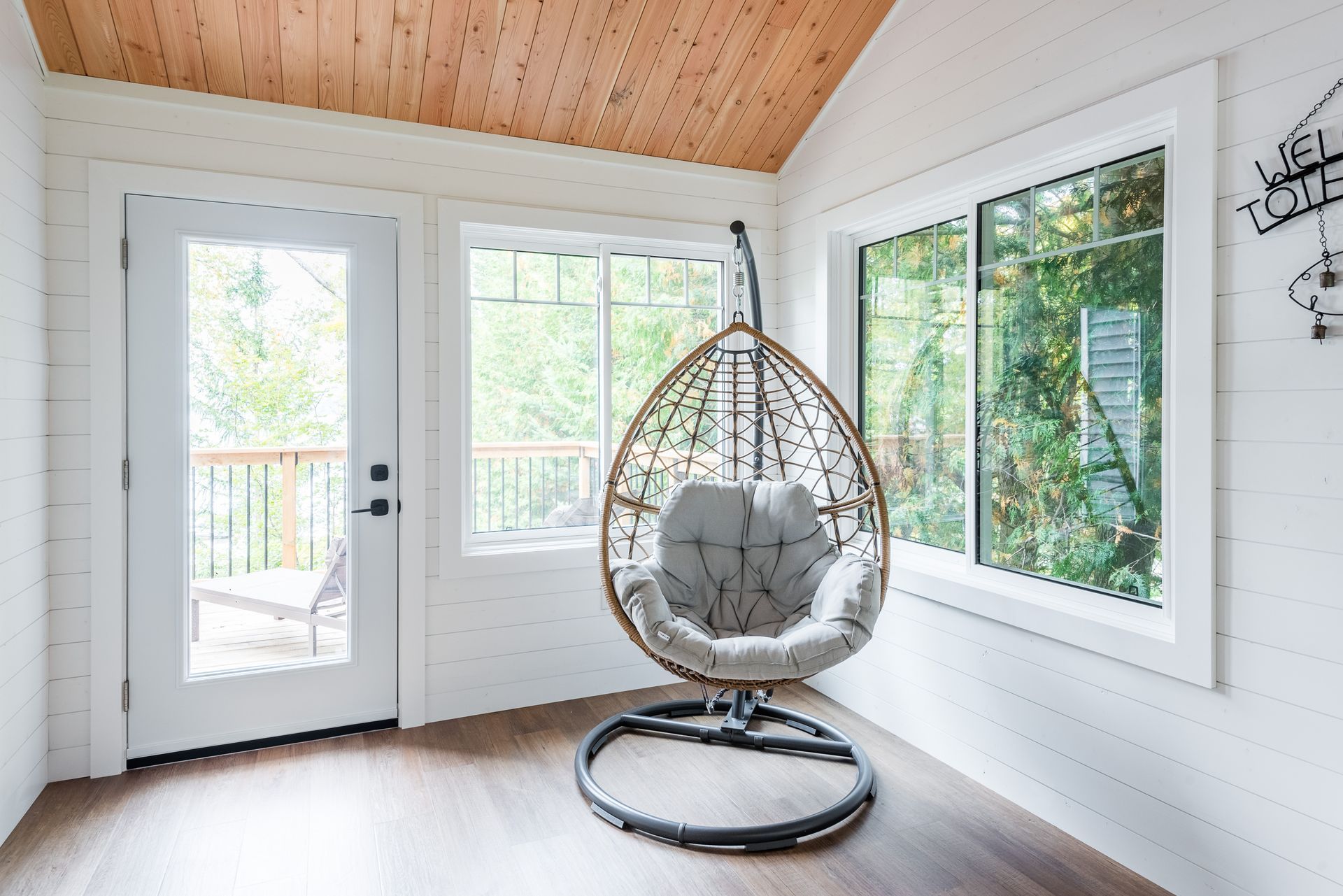 A hanging chair is sitting in a room next to a window.