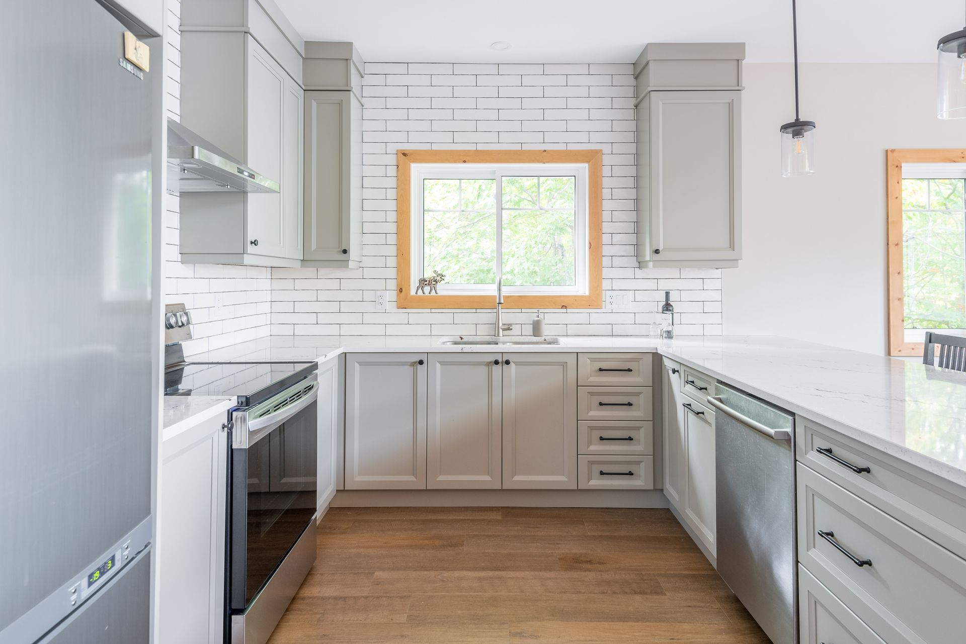 A kitchen with white cabinets , stainless steel appliances , and a large window.