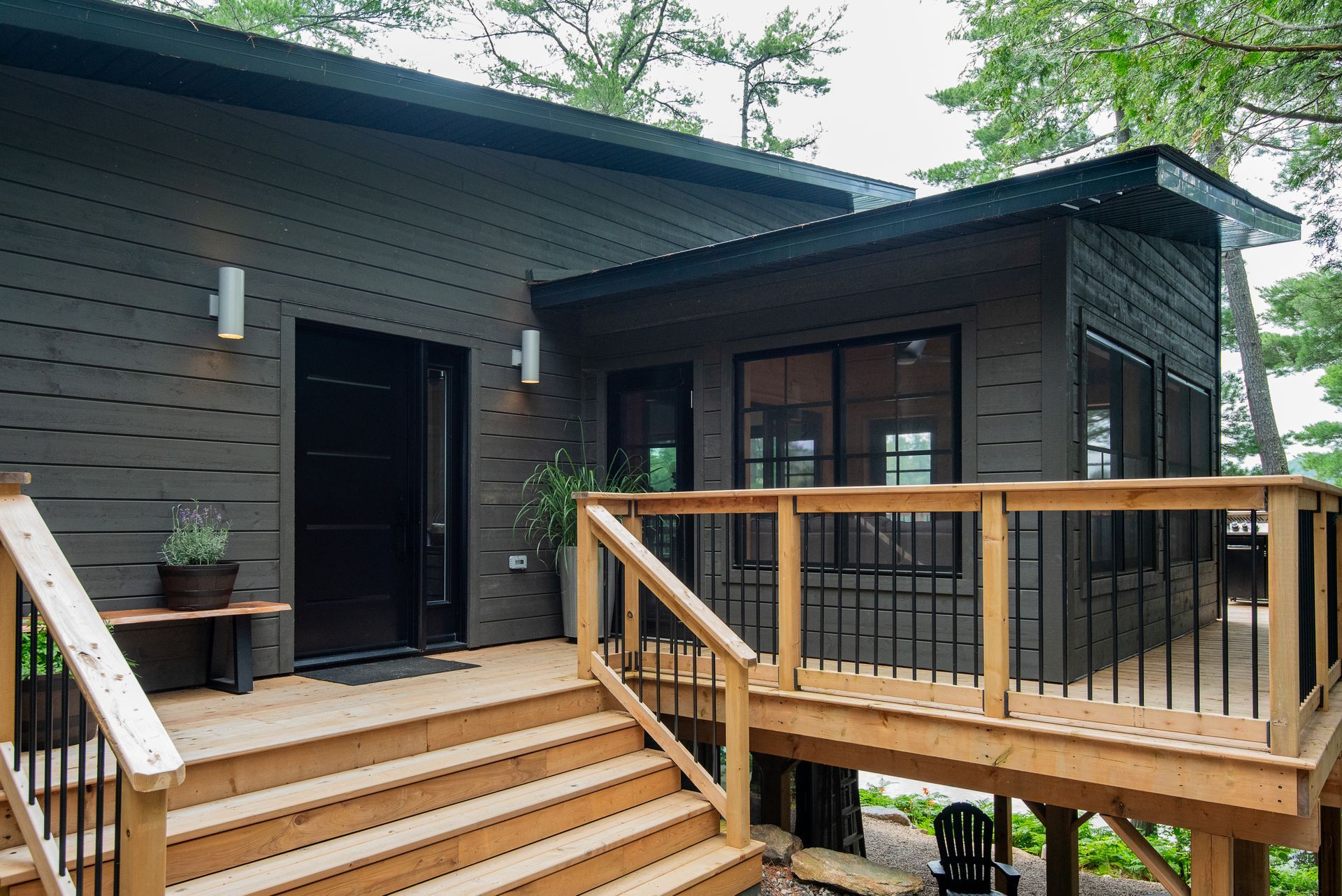A black house with a wooden deck and stairs leading to it.