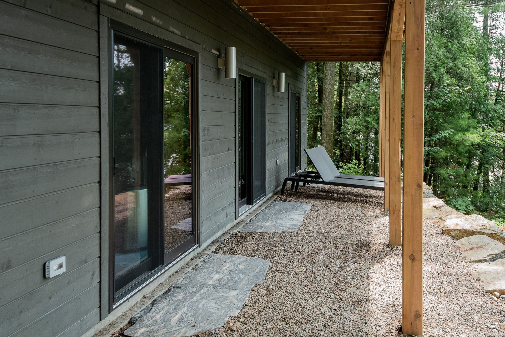 A covered porch with chairs and a sliding glass door