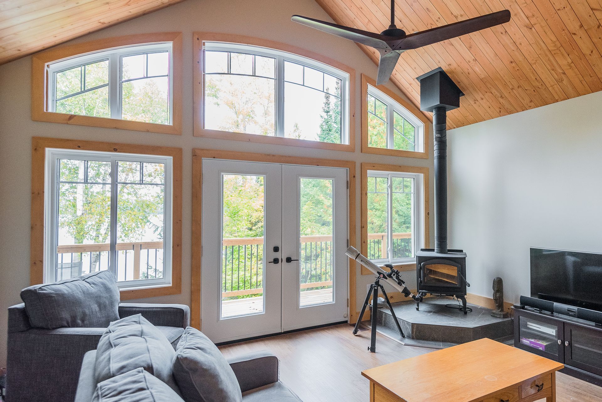 A living room with a lot of windows and a wood stove.