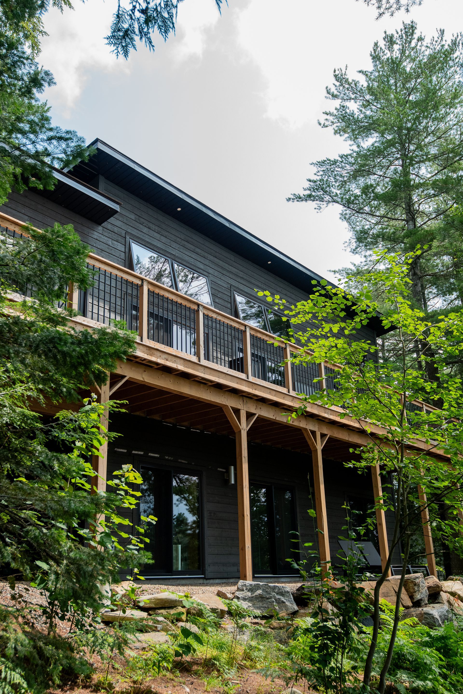 A large house with a large deck is surrounded by trees.