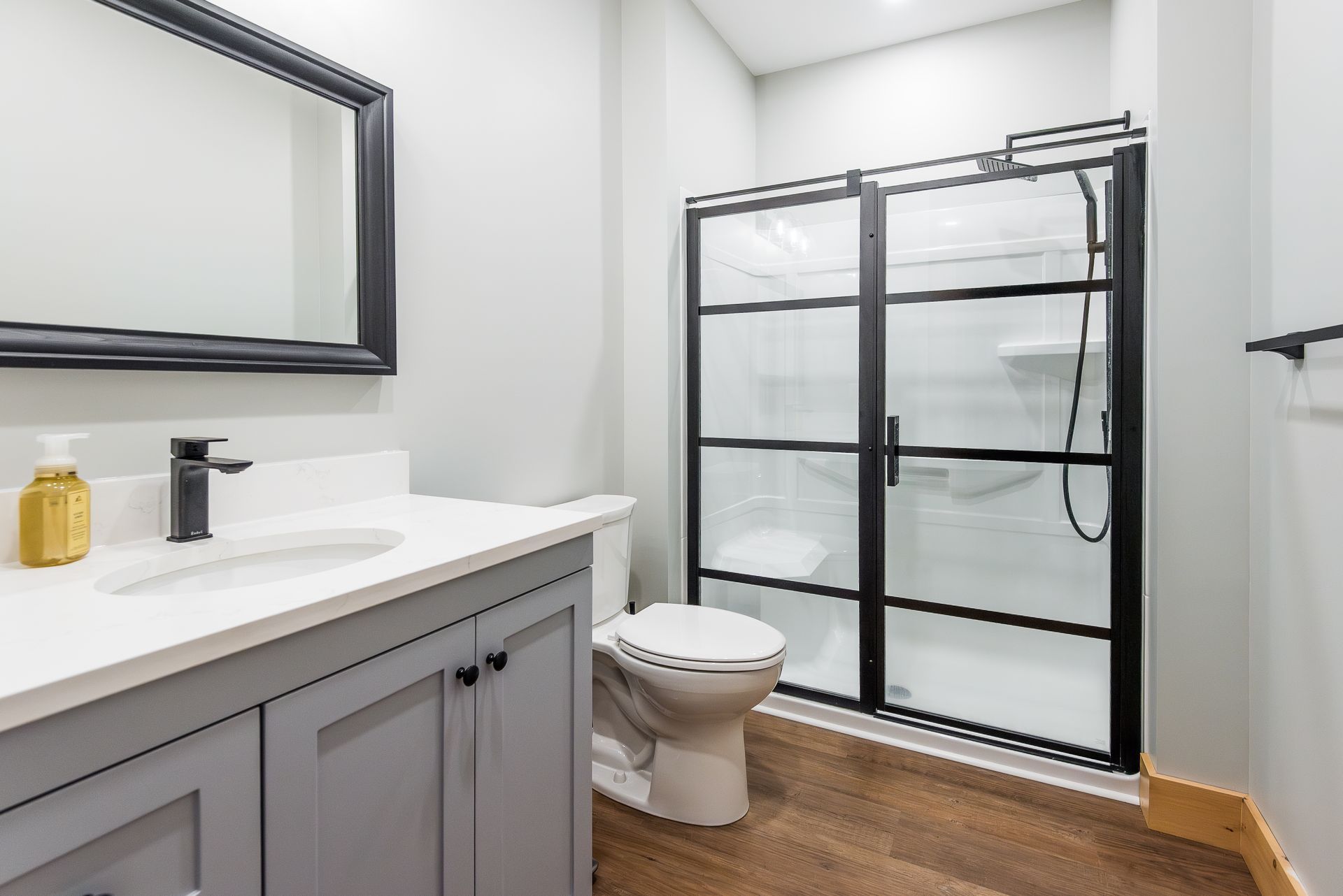 A bathroom with a toilet , sink , mirror and shower stall.