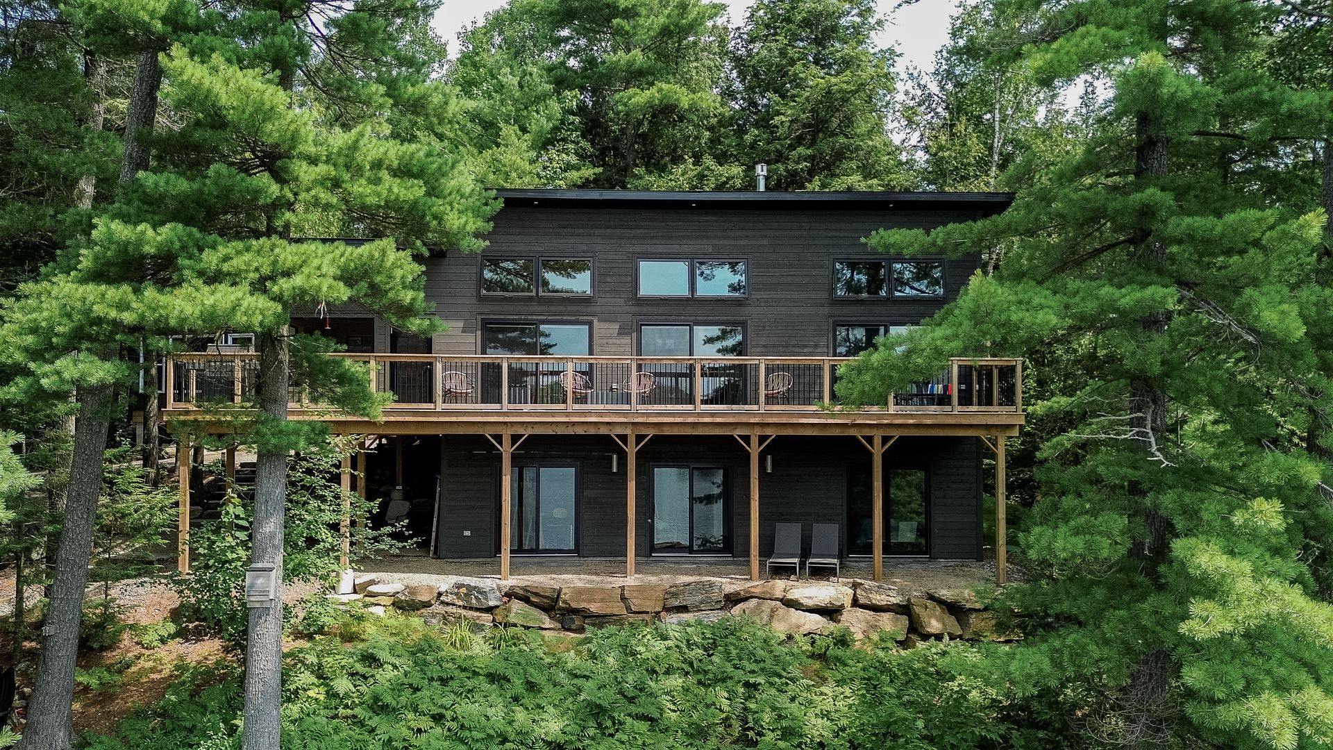 A large house with a large deck is surrounded by trees.