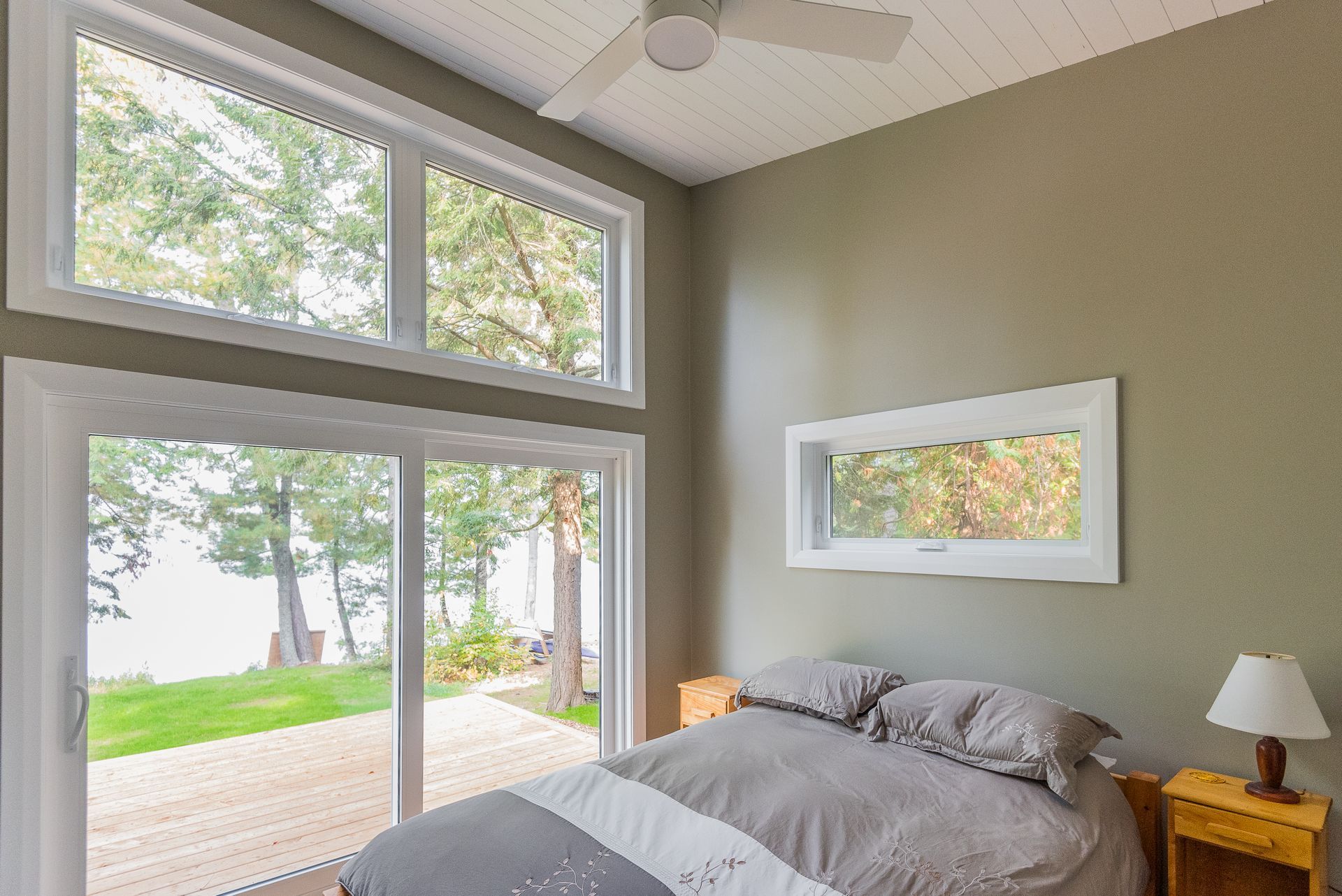 A bedroom with a large bed , sliding glass doors , and a ceiling fan.