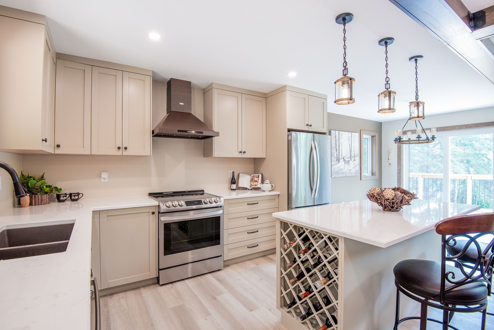 A kitchen with white cabinets , stainless steel appliances , a wine rack and a large island.