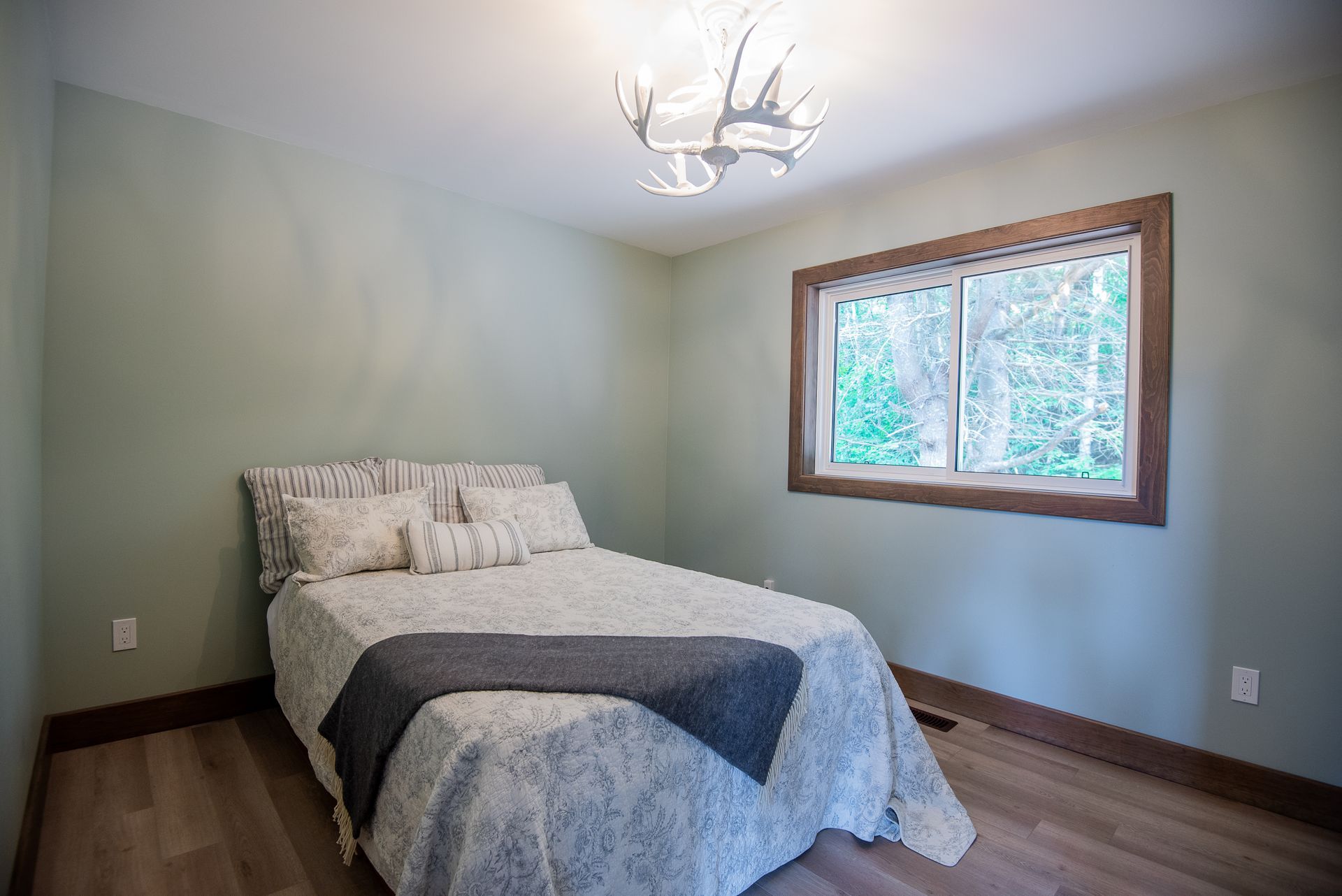A bedroom with a bed , window and chandelier.