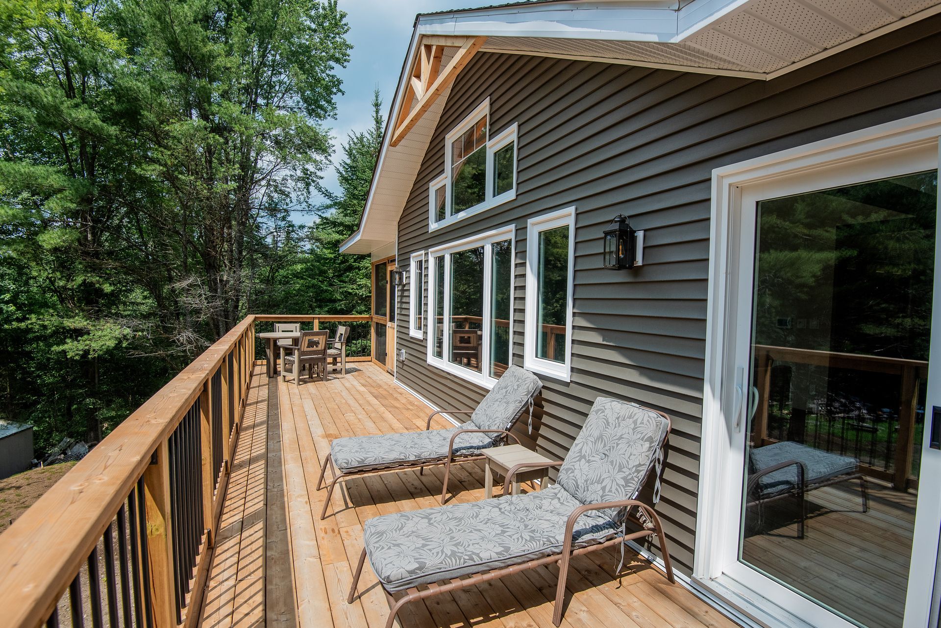 A large house with a large deck with lounge chairs on it