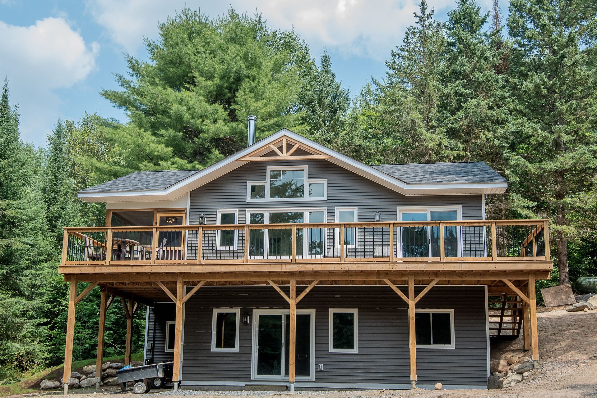 A large house with a large deck is surrounded by trees.