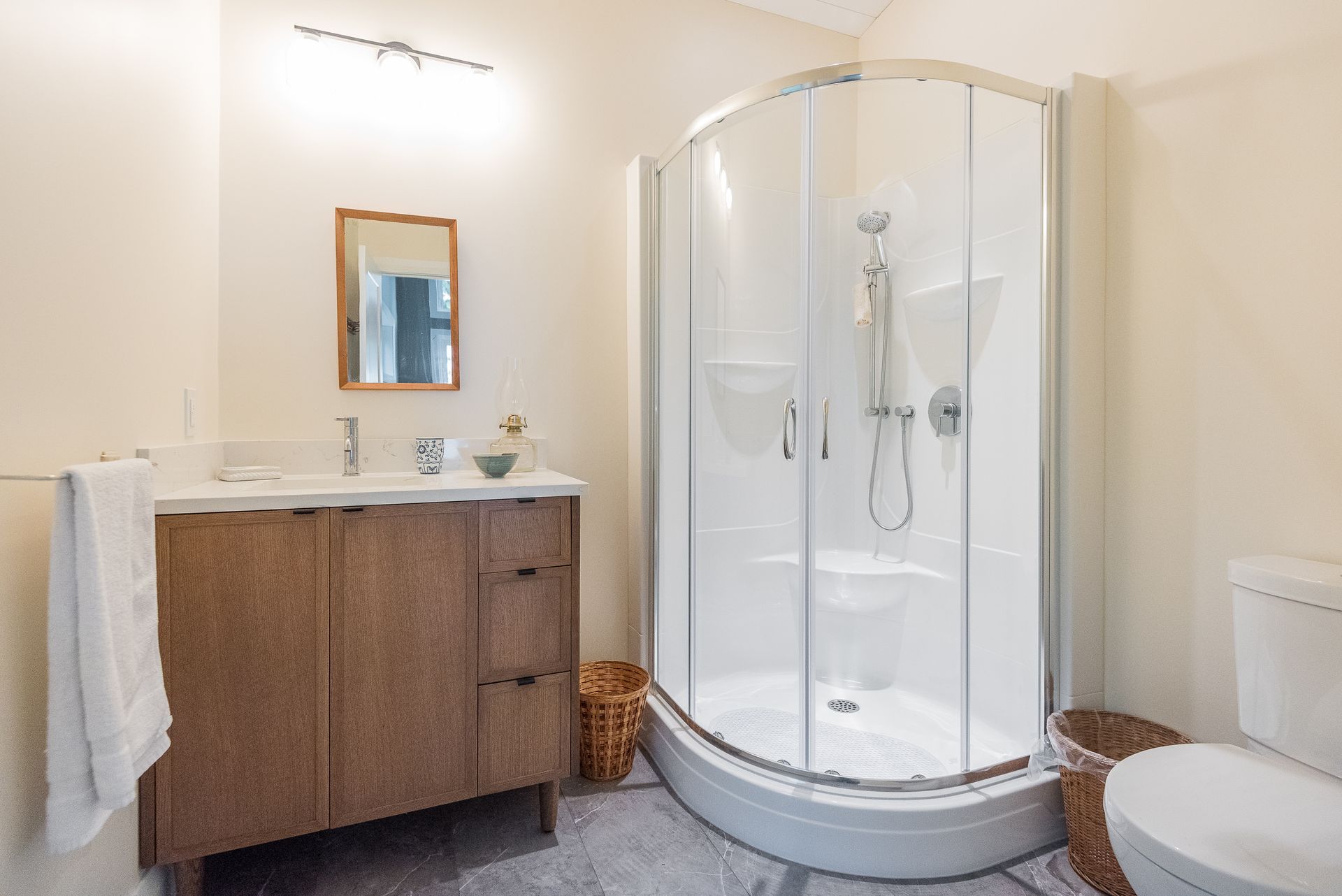 A bathroom with a shower , toilet , sink and mirror.