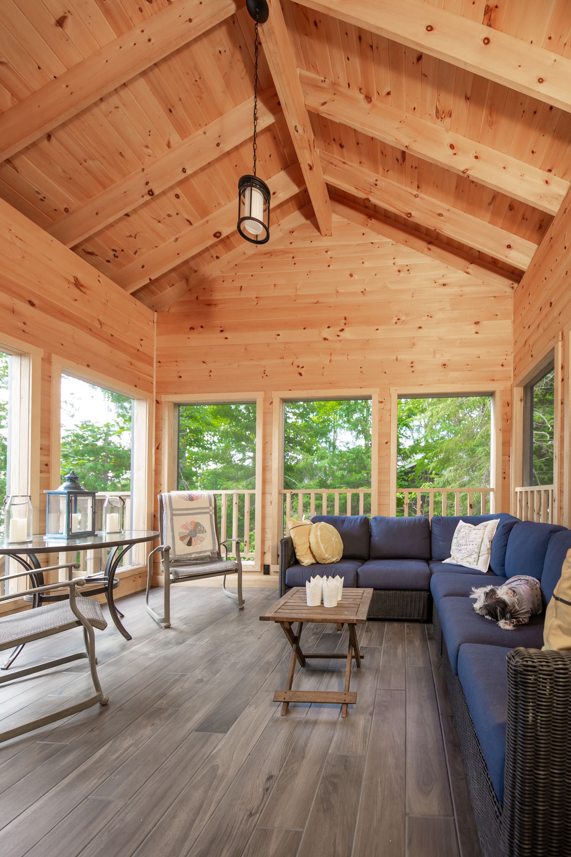 A screened in porch with a blue sectional couch and a table.