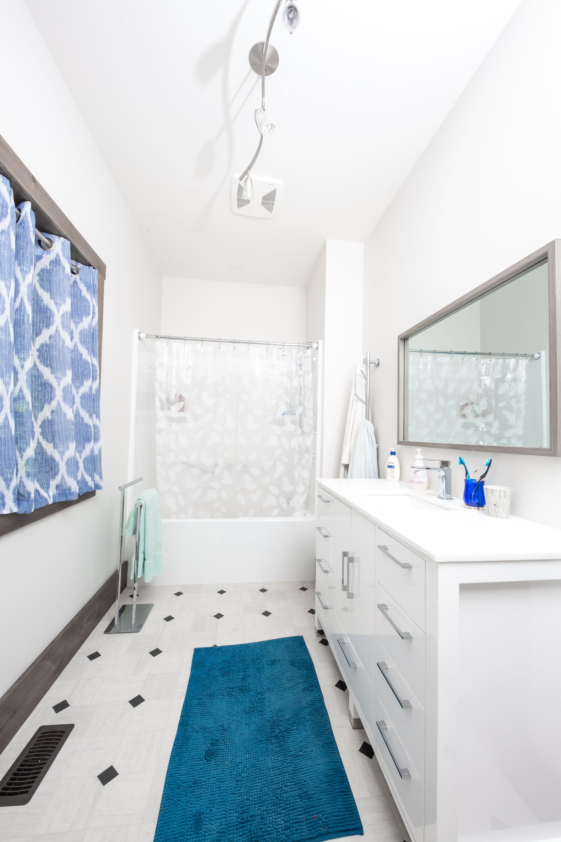 A bathroom with a blue rug and a blue shower curtain.