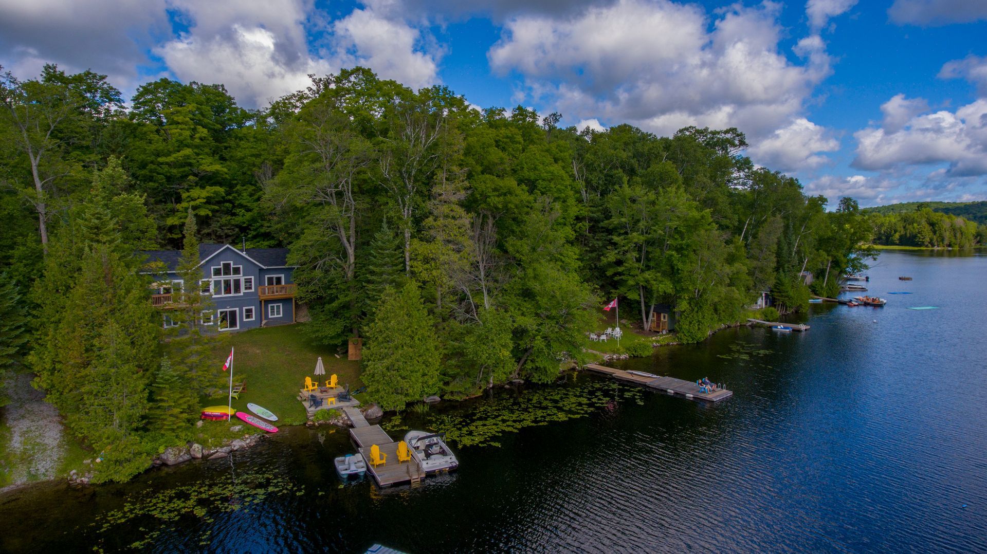 An aerial view of a house on the shore of a lake surrounded by trees.