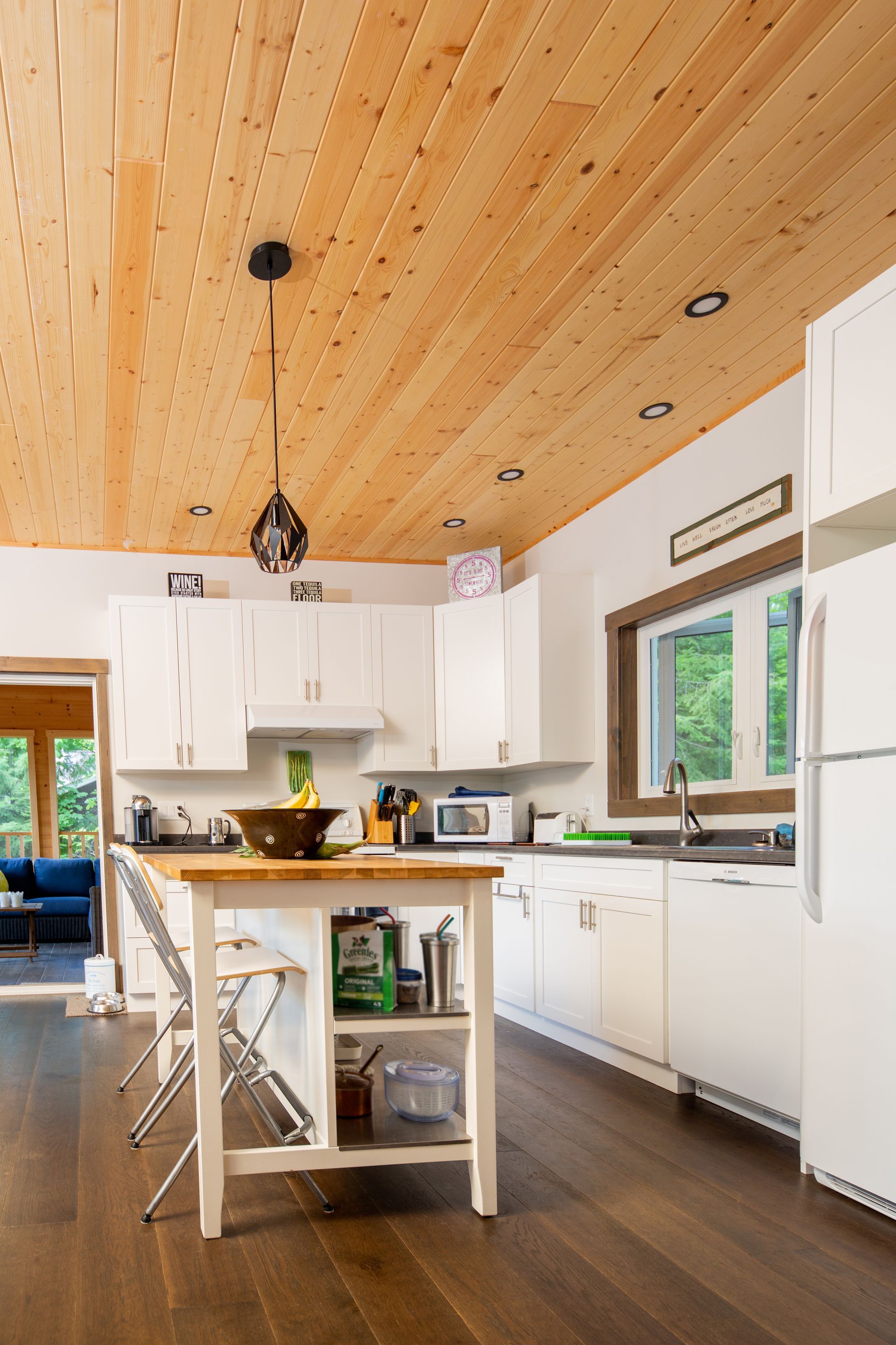 A kitchen with a wooden ceiling and white cabinets.