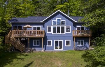 A large blue house with a lot of windows is surrounded by trees.