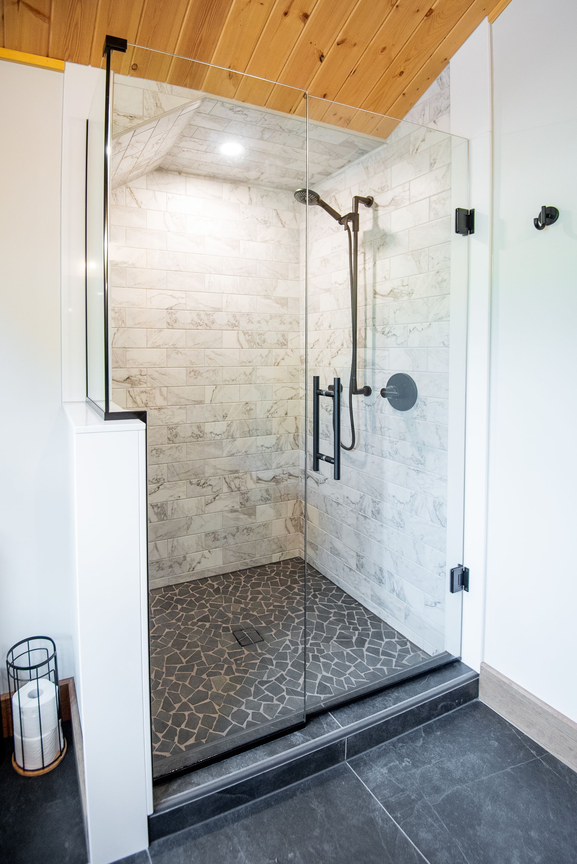 A bathroom with a walk in shower with a glass door.