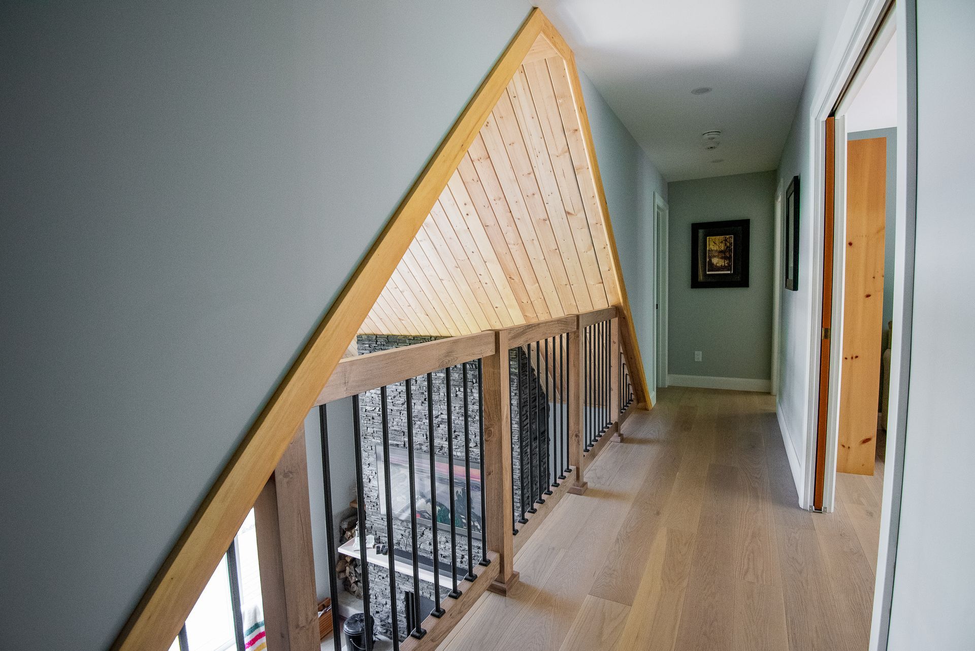 A hallway with a wooden railing and stairs leading up to the second floor.