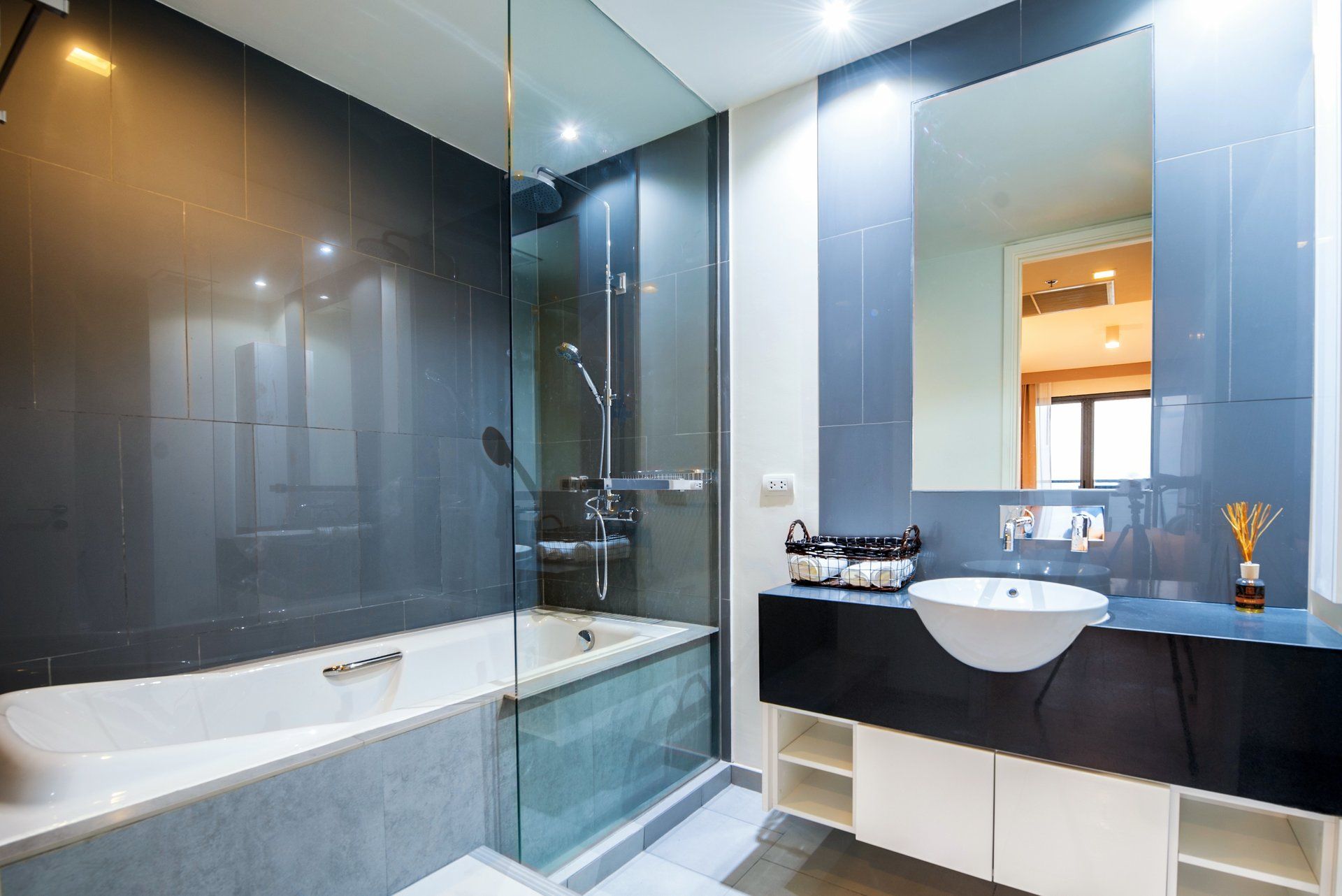 bathroom with a frameless glass splash guard installed on the tub next  to the sink