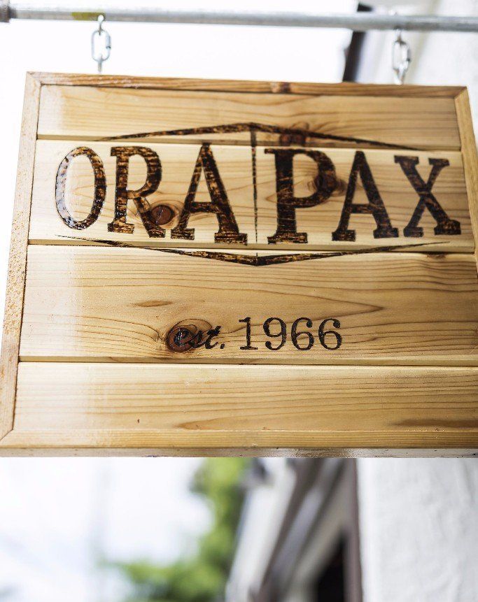 A wooden sign that says ora pax on it