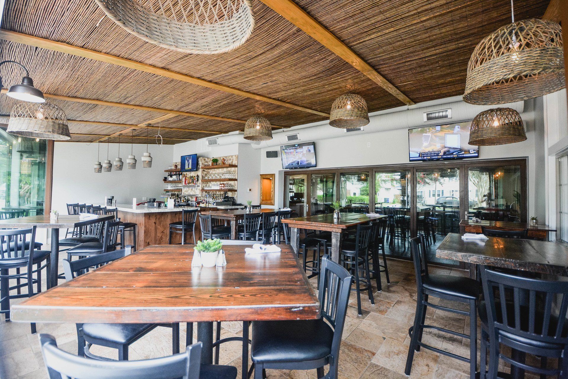 A restaurant with tables and chairs and a thatched roof.