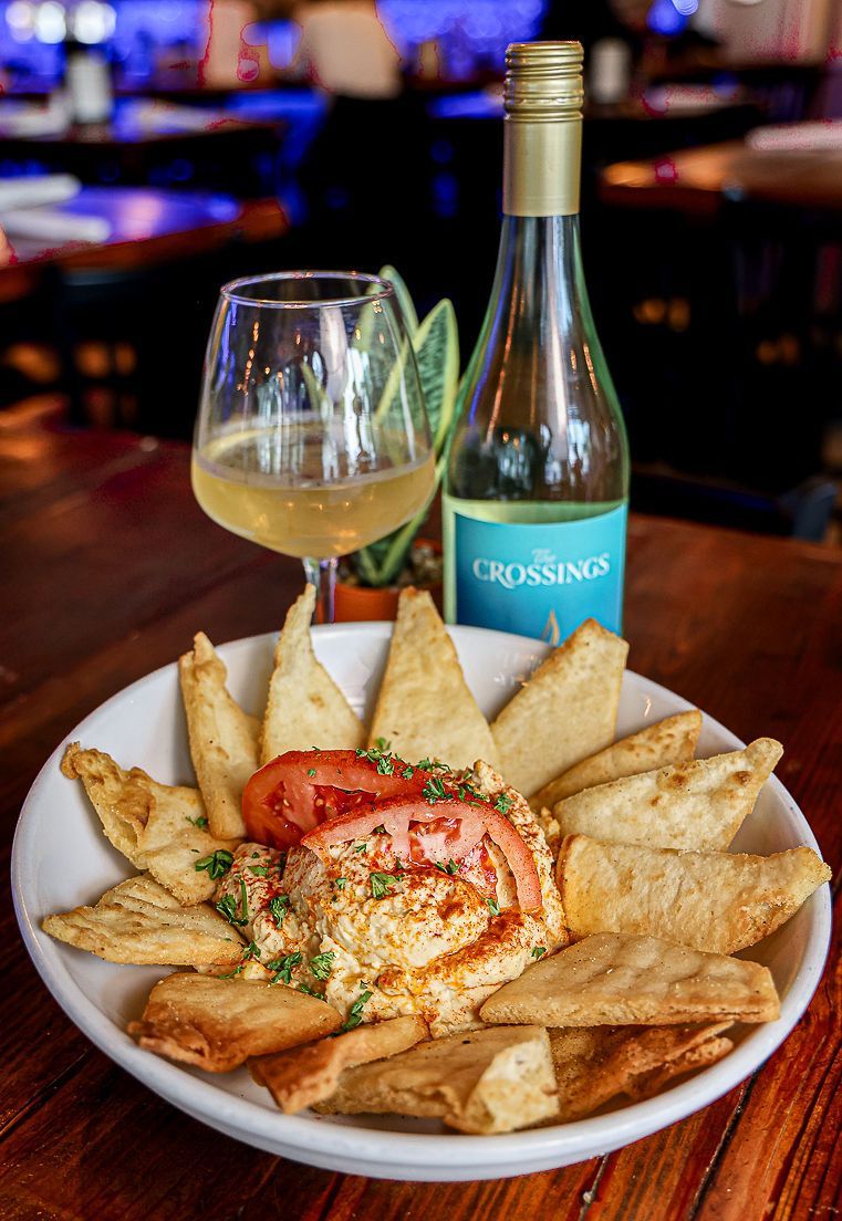 A plate of food and a glass of wine on a table.