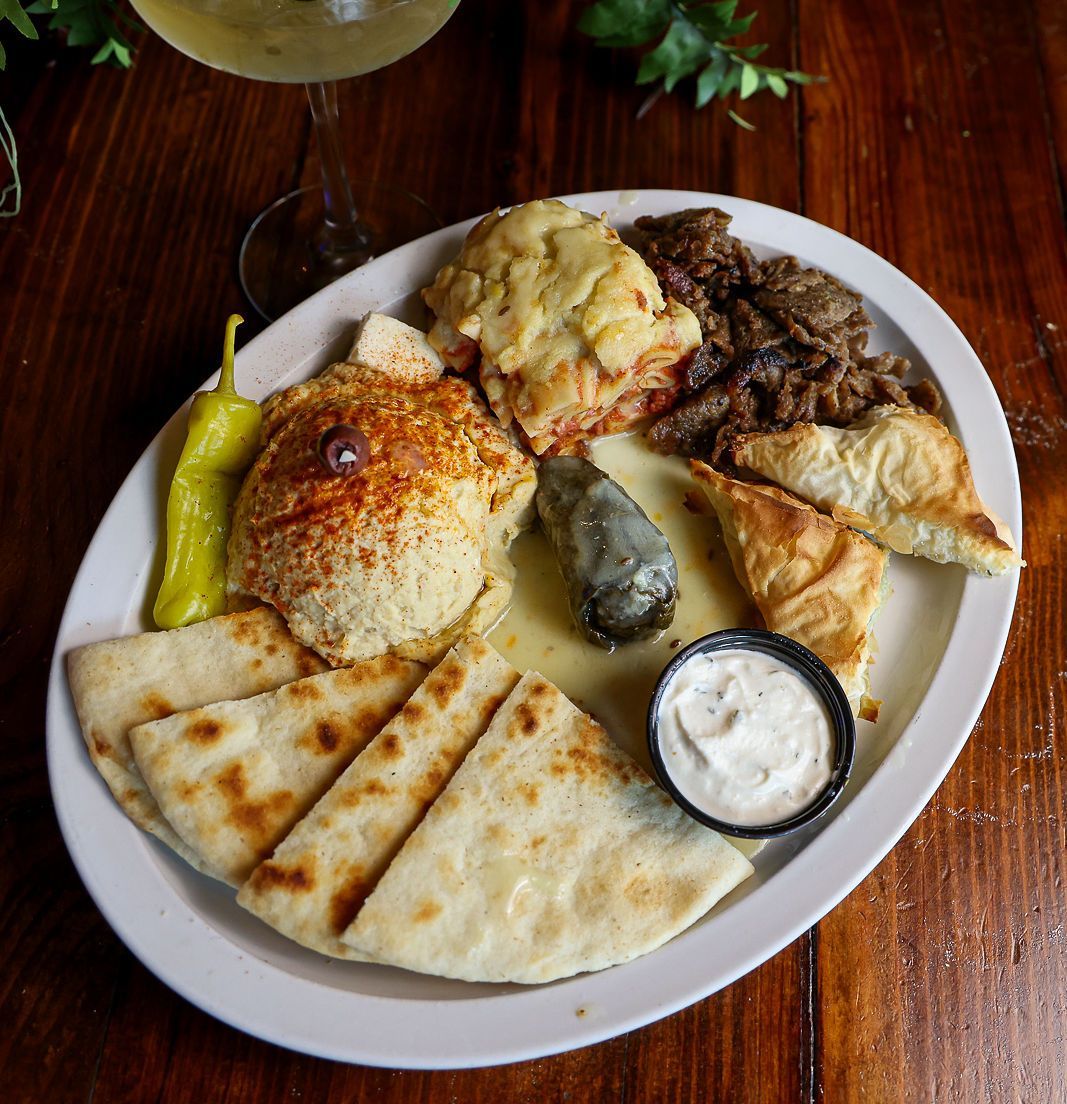 A plate of food on a wooden table next to a glass of wine