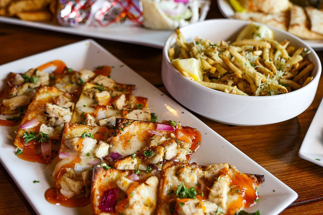 A table topped with plates of food and a bowl of french fries.