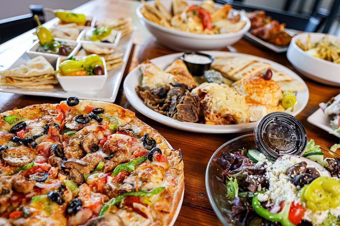 A table topped with plates of food and a pizza.