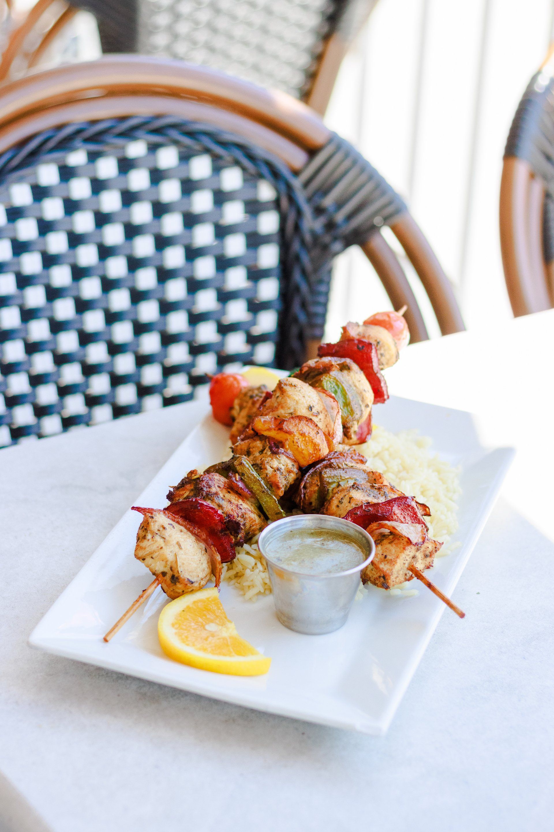 A white plate topped with chicken skewers and rice on a table.