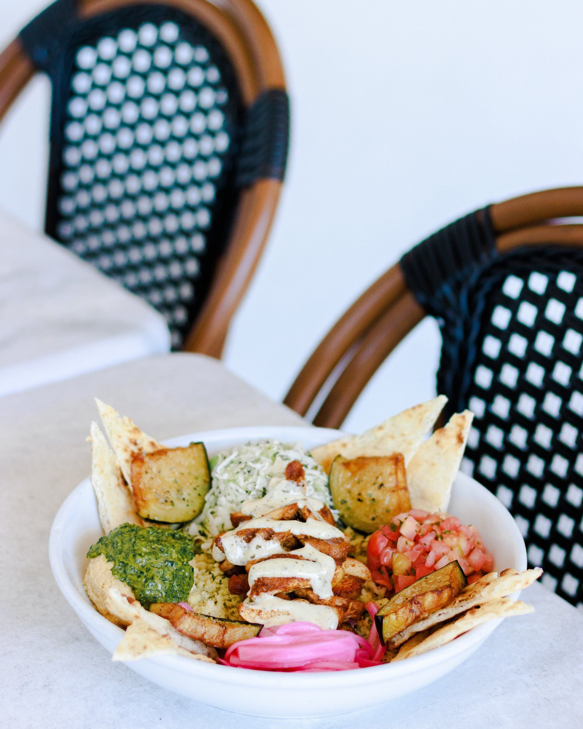 A bowl of food is sitting on a table next to two chairs.