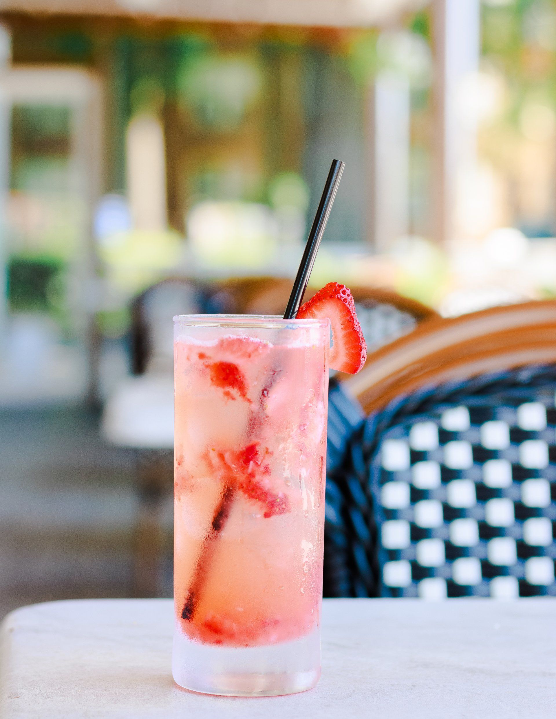 A glass of pink liquid with strawberries on a table.