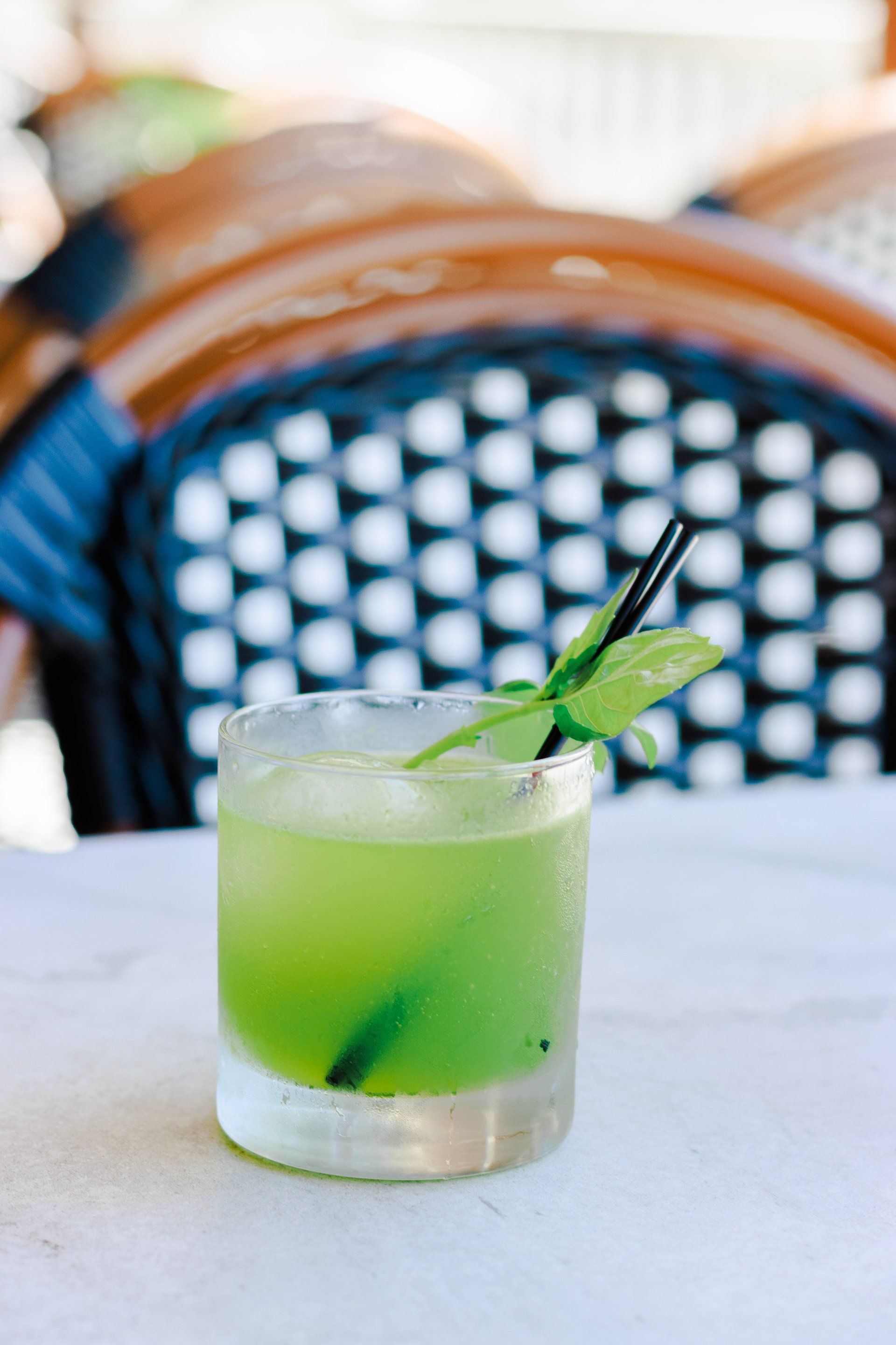 A green drink with a straw in it is on a table.