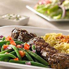 A plate of food with meat , green beans and rice on a table.