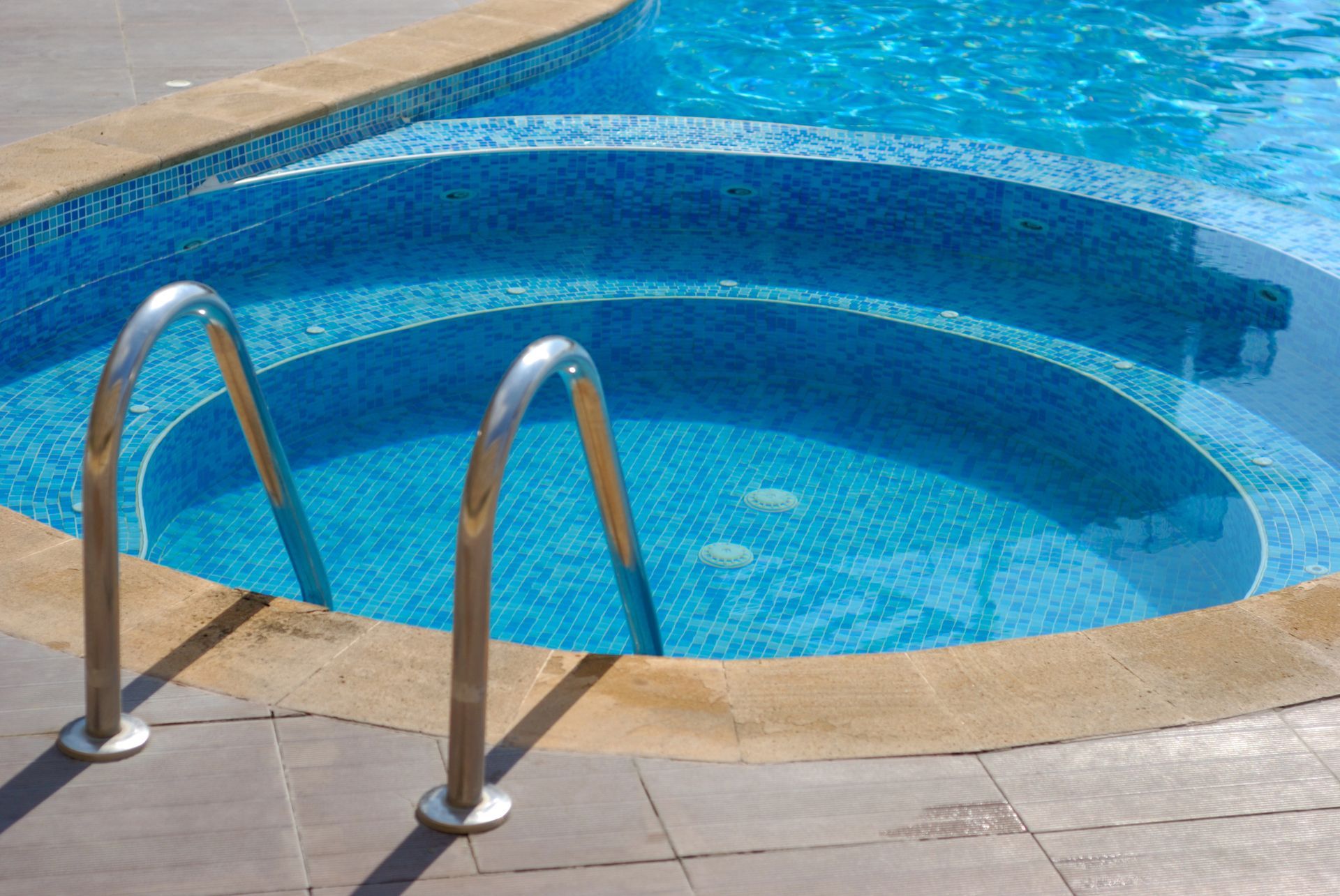 Piscina con jacuzzi de azulejos azules y escalera.