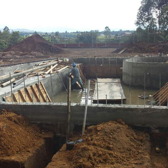 Obra de construcción con encofrados de hormigón, un trabajador y movimiento de tierras.