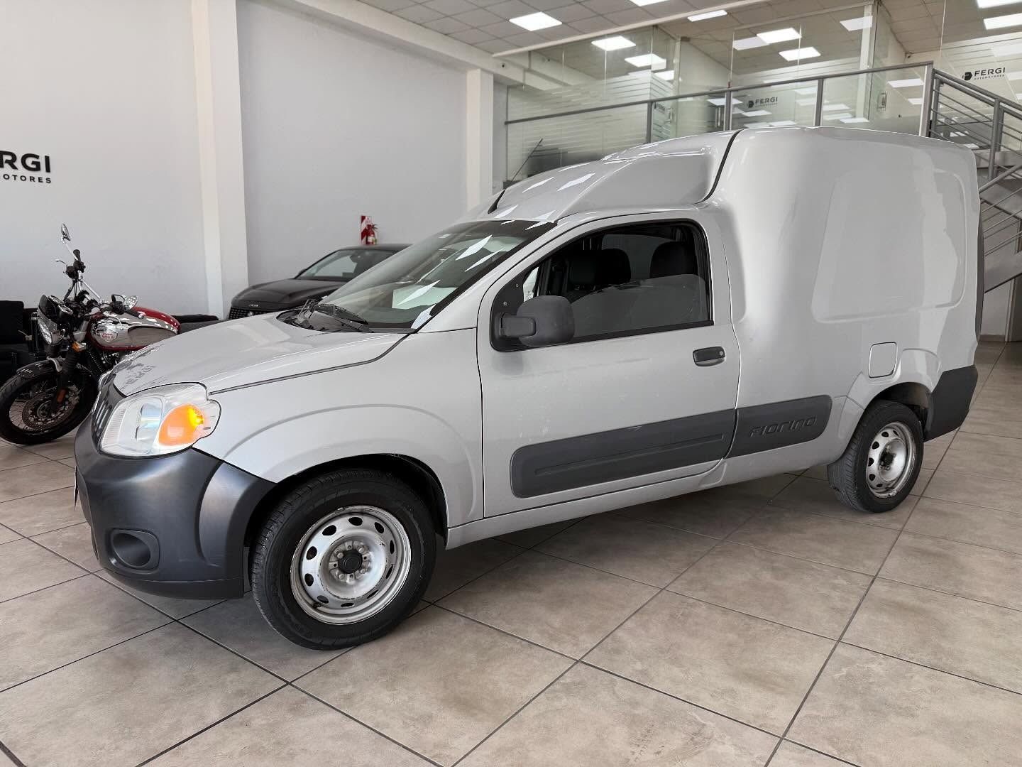 Furgoneta de carga plateada estacionada dentro de una sala de exposición.