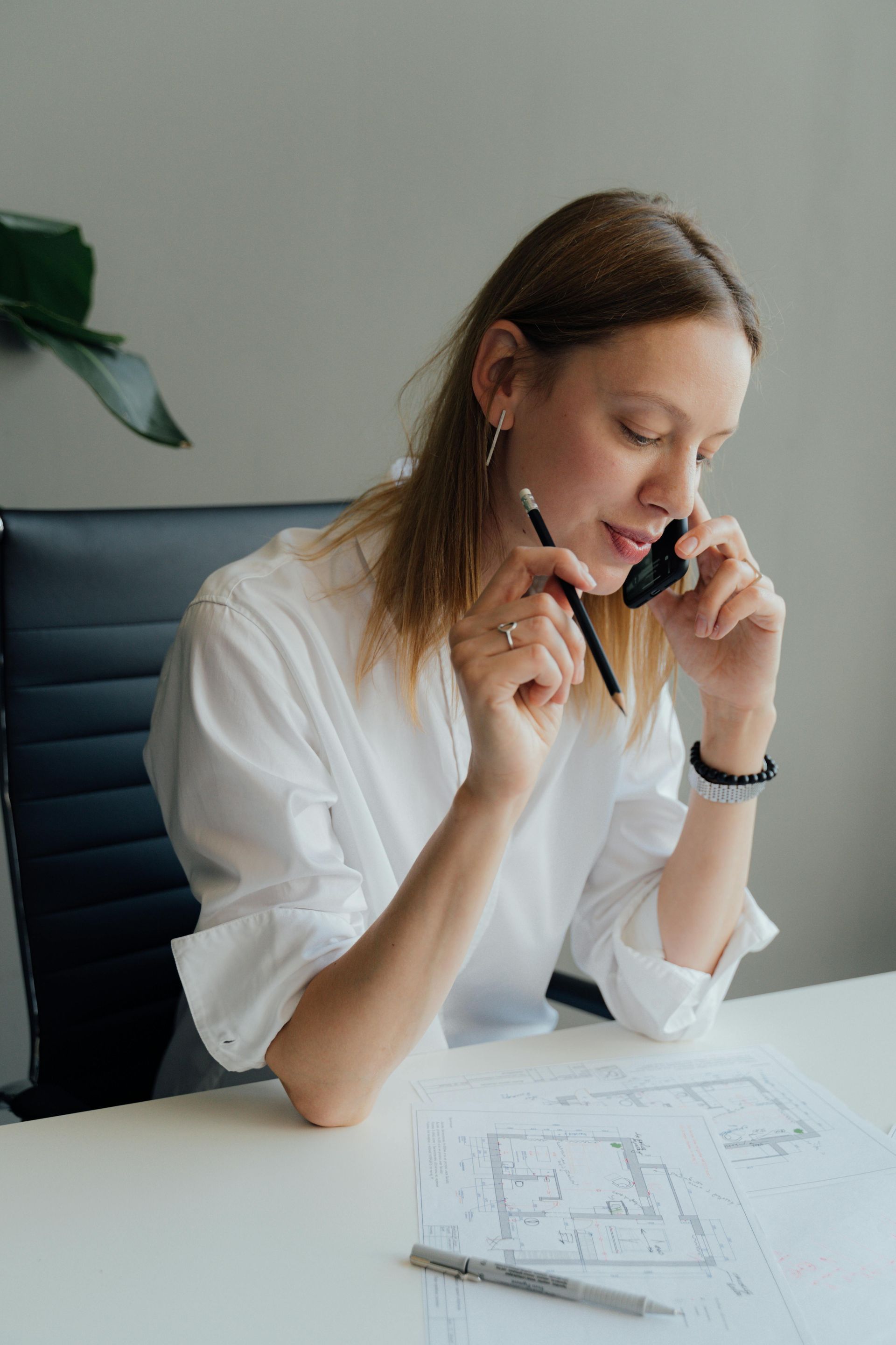 A woman is sitting at a desk talking on a cell phone.